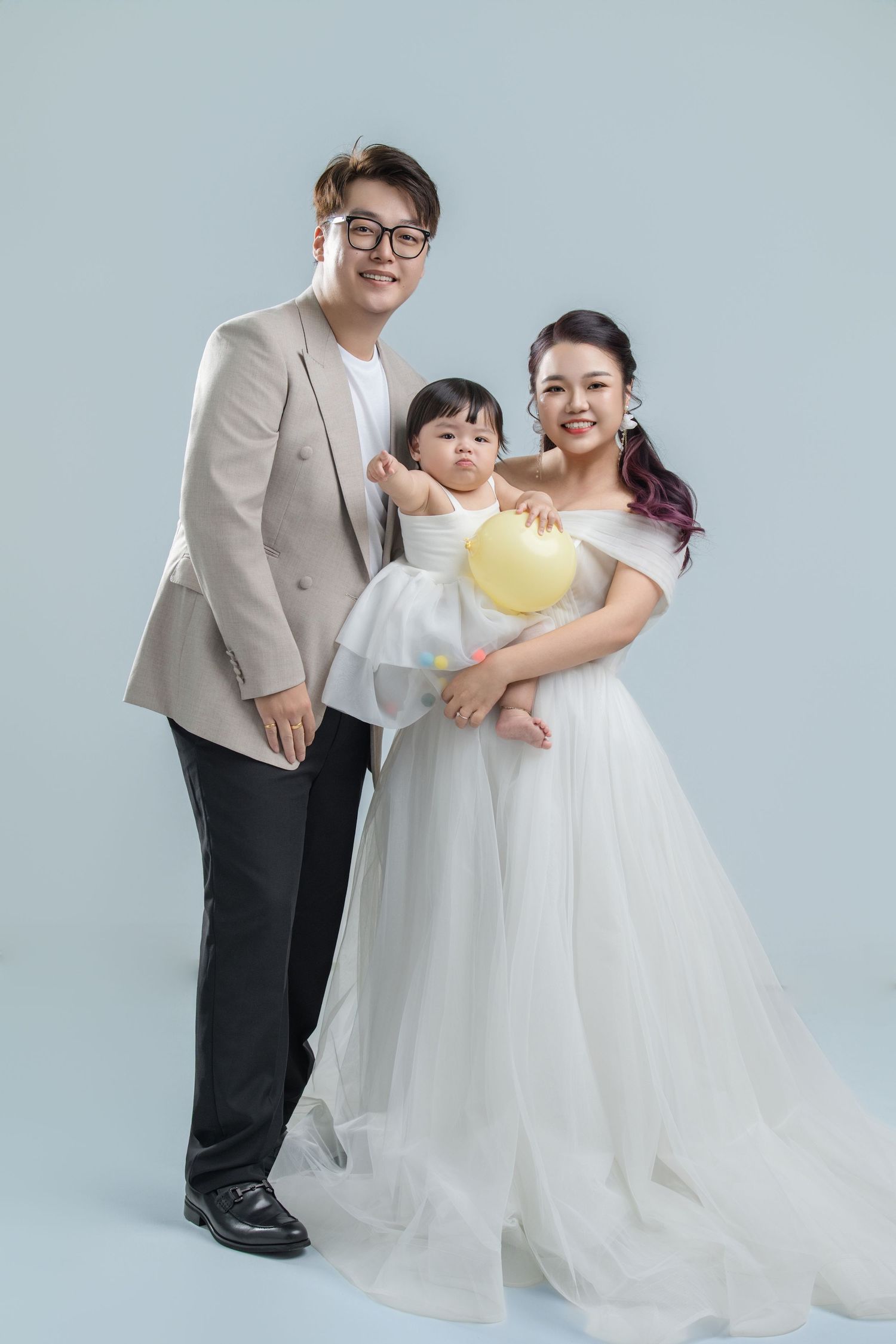 Family portrait session in formal attire against light gray backdrop showing loving embraces and interactions.