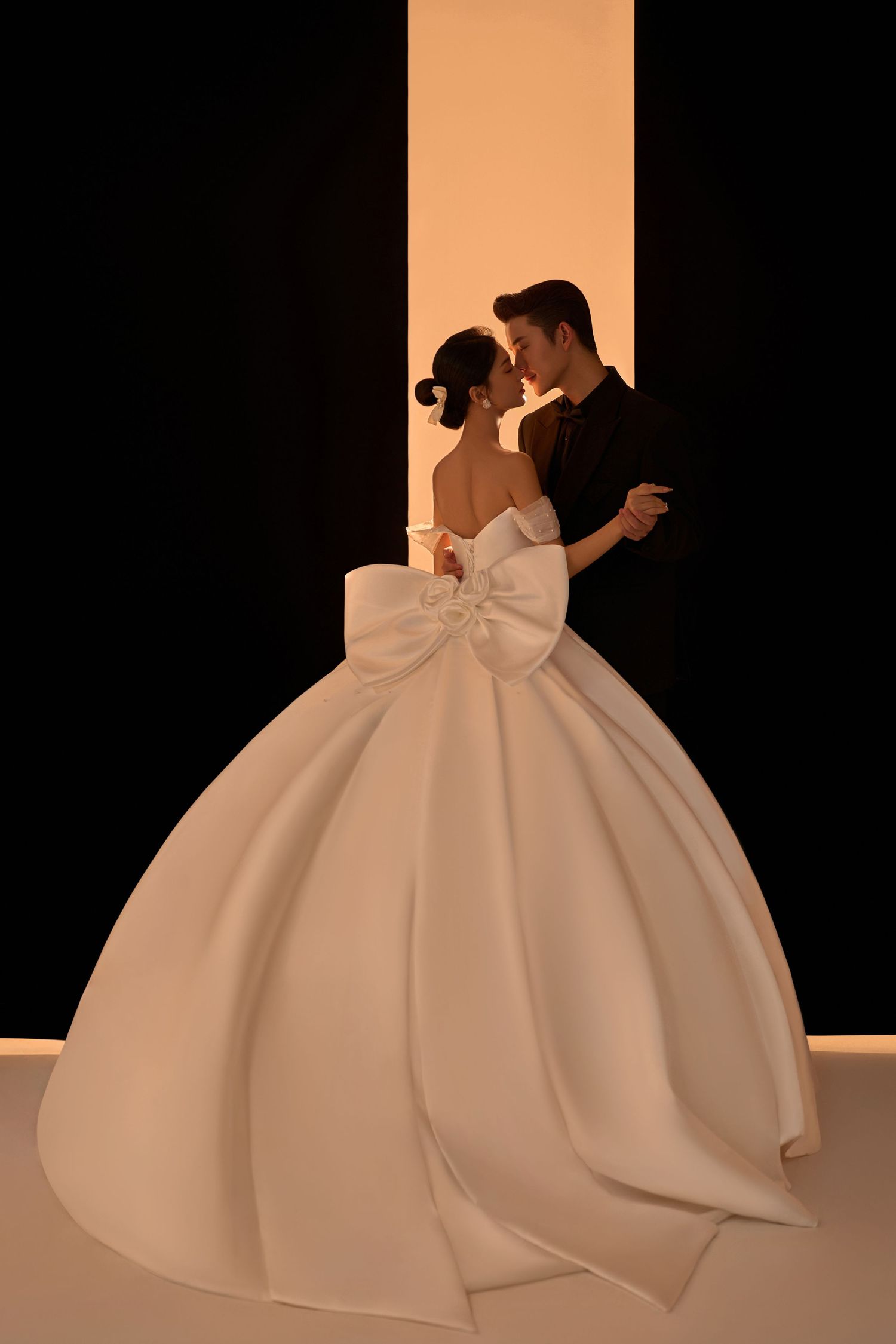 A dramatic series showing two people in formal wedding attire dancing and embracing against a black background.