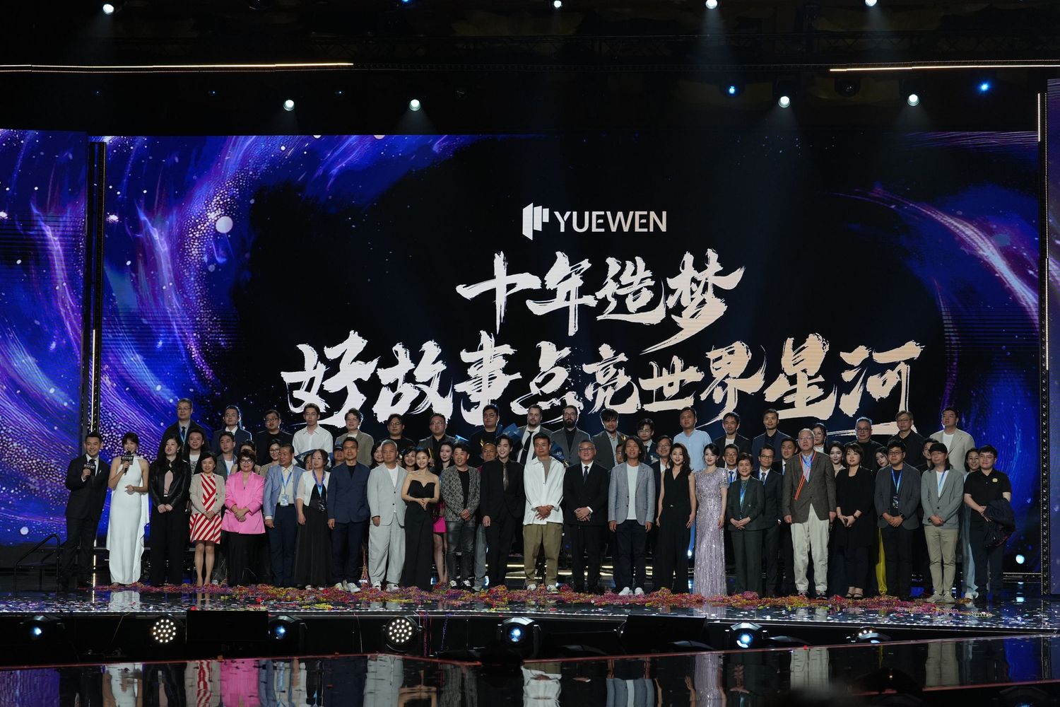 Yuewen Group 10th anniversary celebration event with large group on stage under colorful lights.