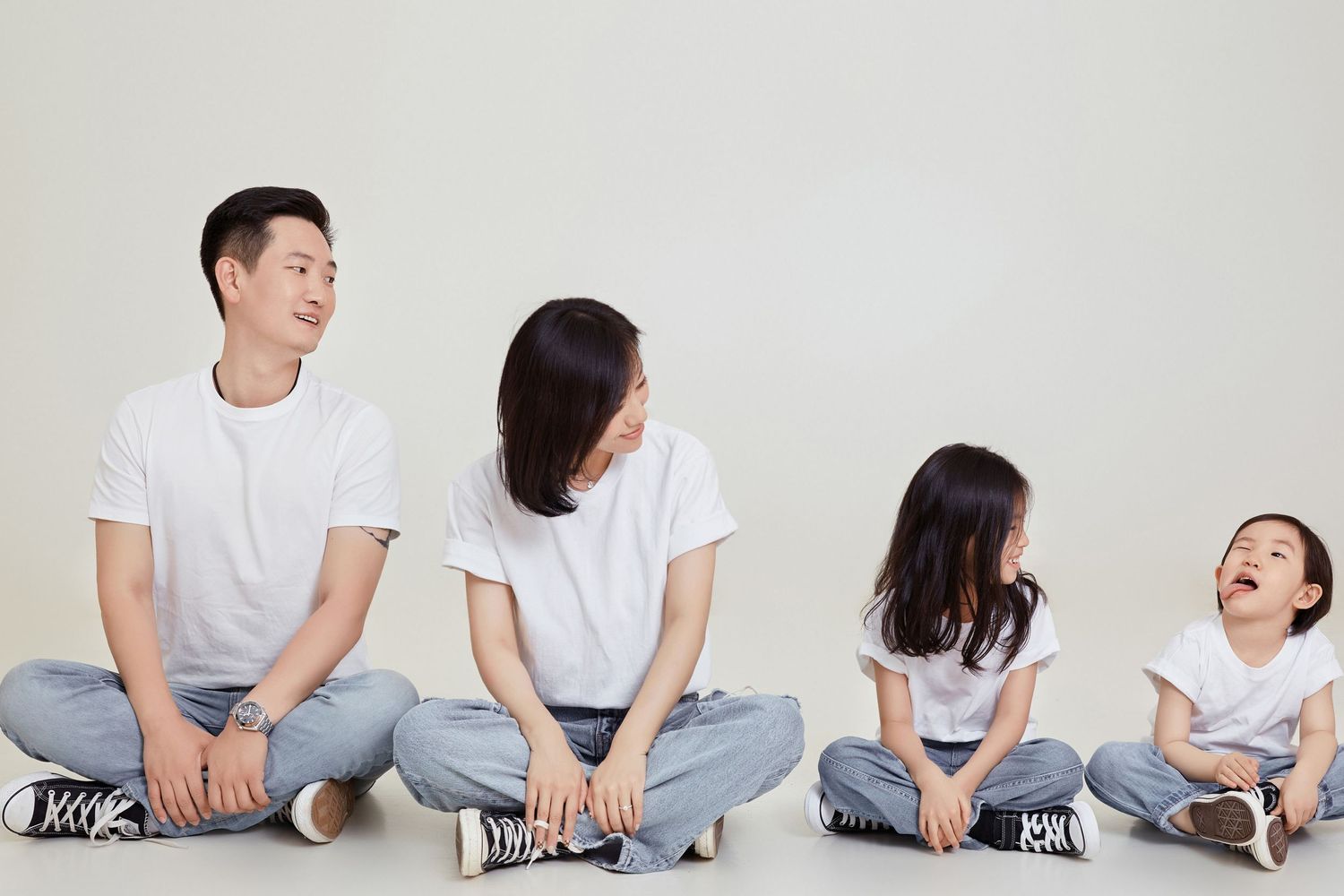 People in white shirts and jeans sit casually in a row against a light gray background.