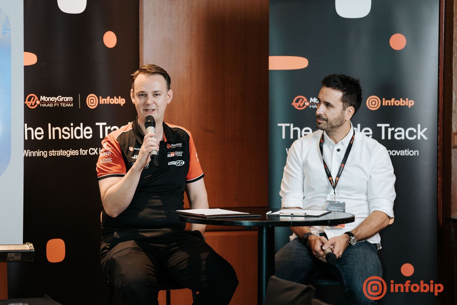 Two men speaking at an Infobip Inside Track event panel discussion, seated in front of branded banners.