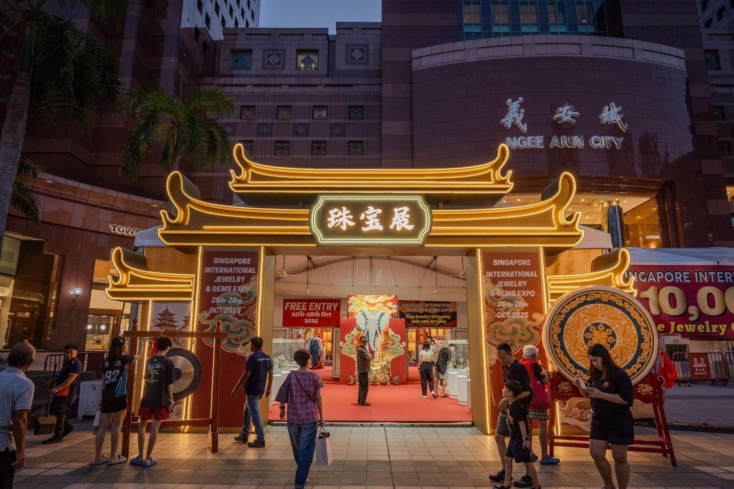 Illuminated traditional Chinese gate entrance to Ngee Ann City jewelry exhibition at dusk in Singapore.