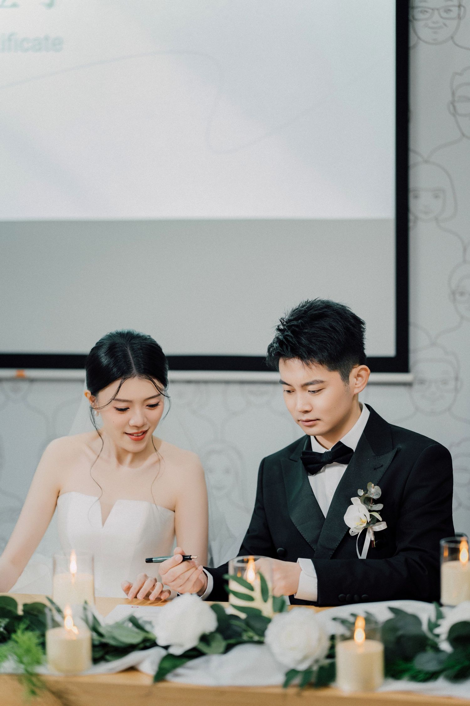 A couple seated at their wedding reception table with white decor and candlelight creates an intimate moment together.