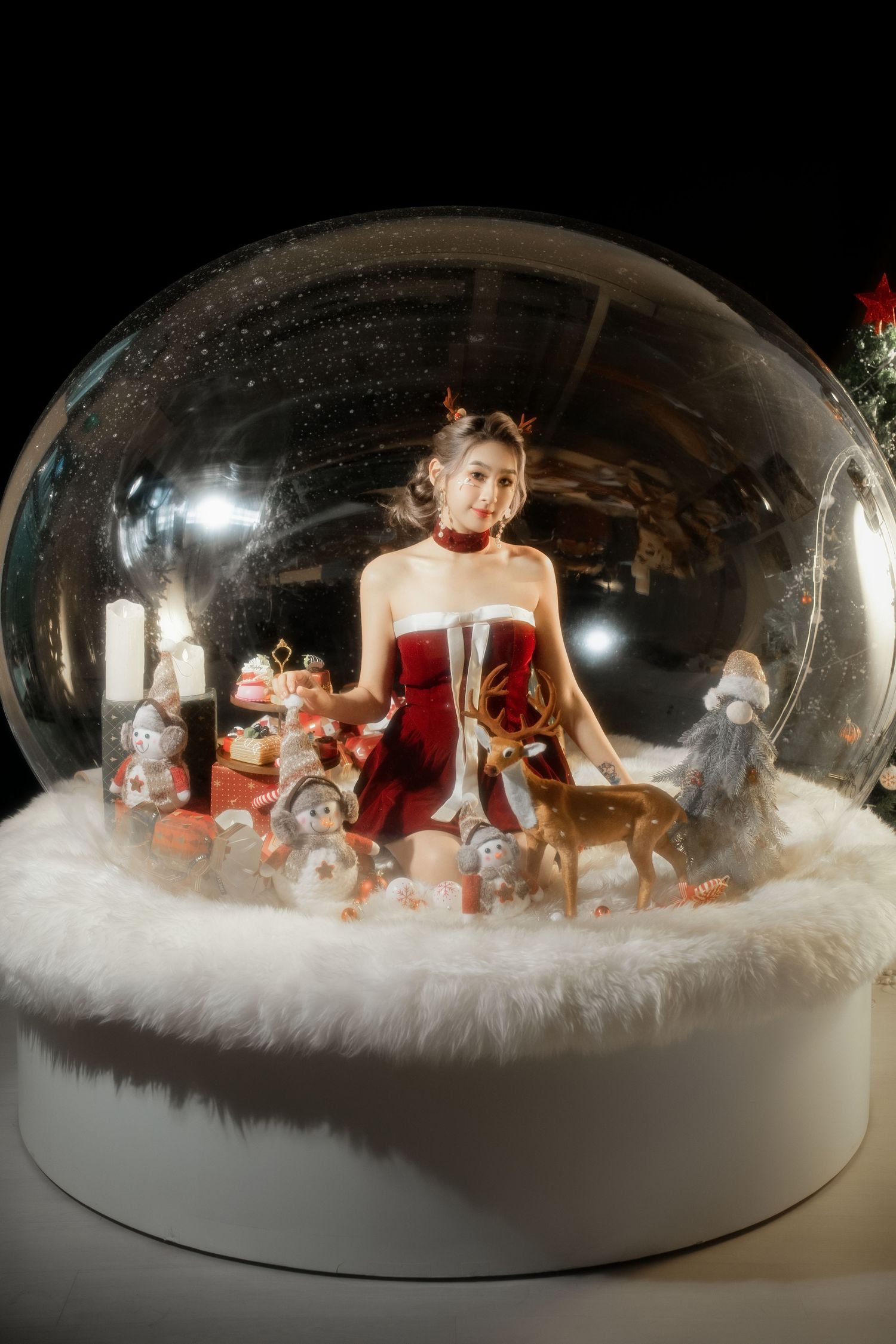 A snow globe display sequence showing figures in a winter scene with red accents and white cotton snow base.
