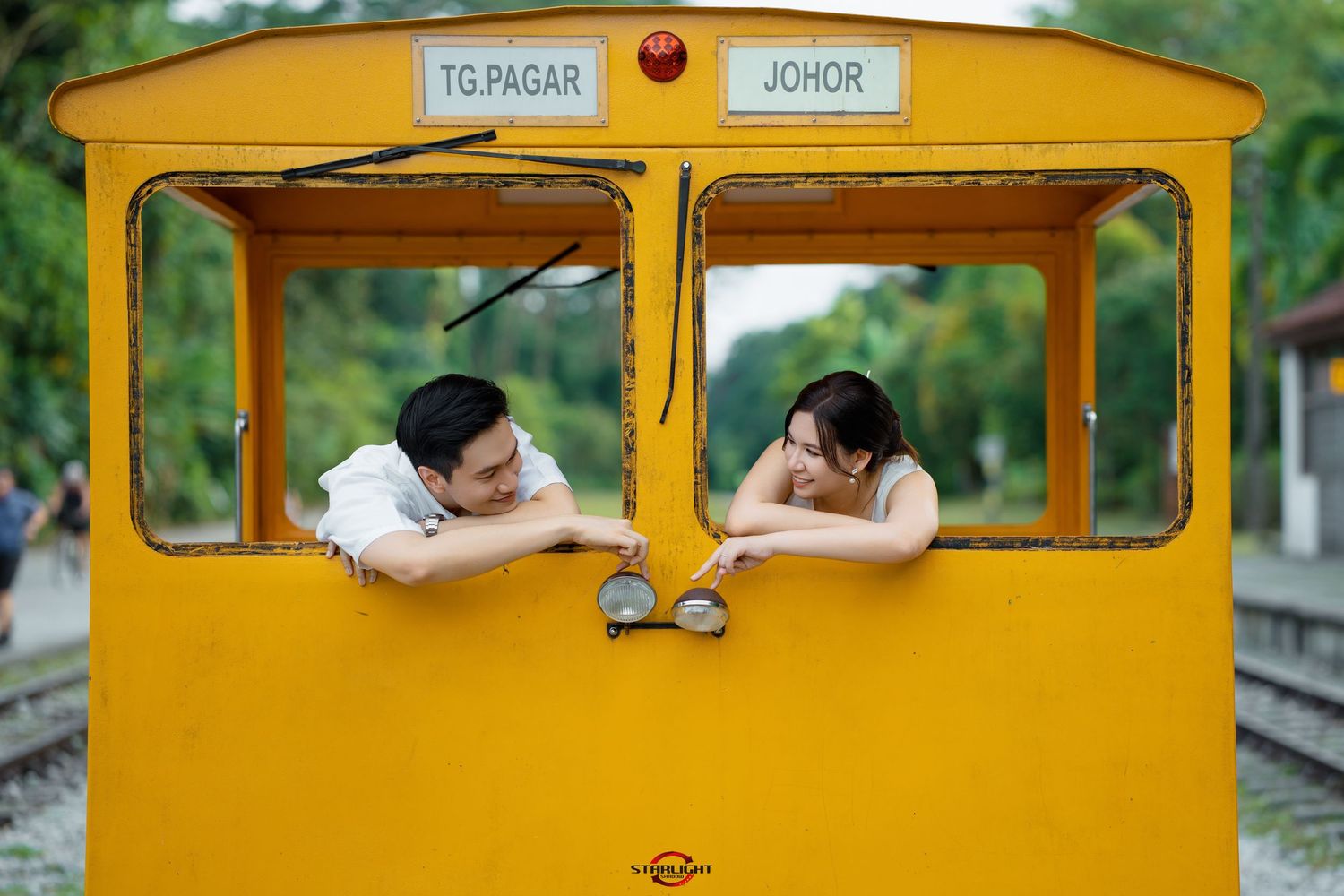 People playfully pose and peek through the windows of a bright yellow school bus parked outdoors.