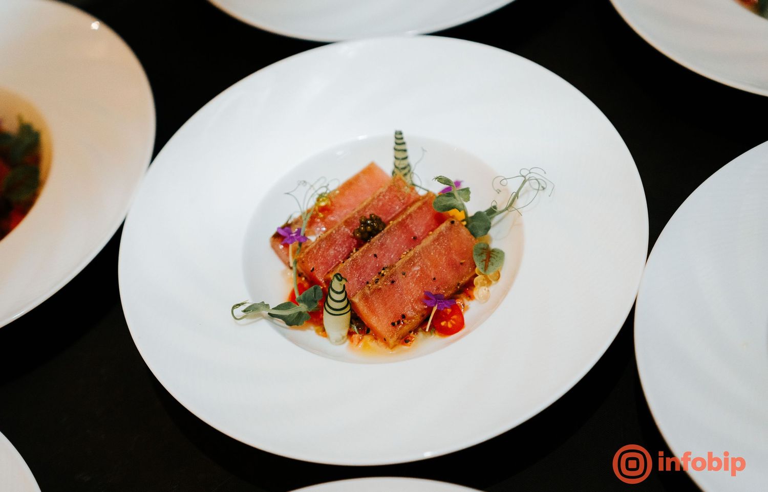 Elegant plated salmon dish with microgreens and garnish on a white plate at a fine dining event.