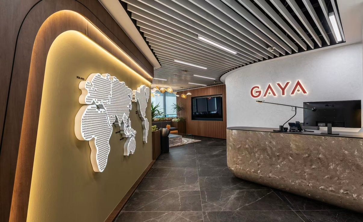 GAYA office reception desk featuring a world map wall art, warm wood accents, and modern interior design.