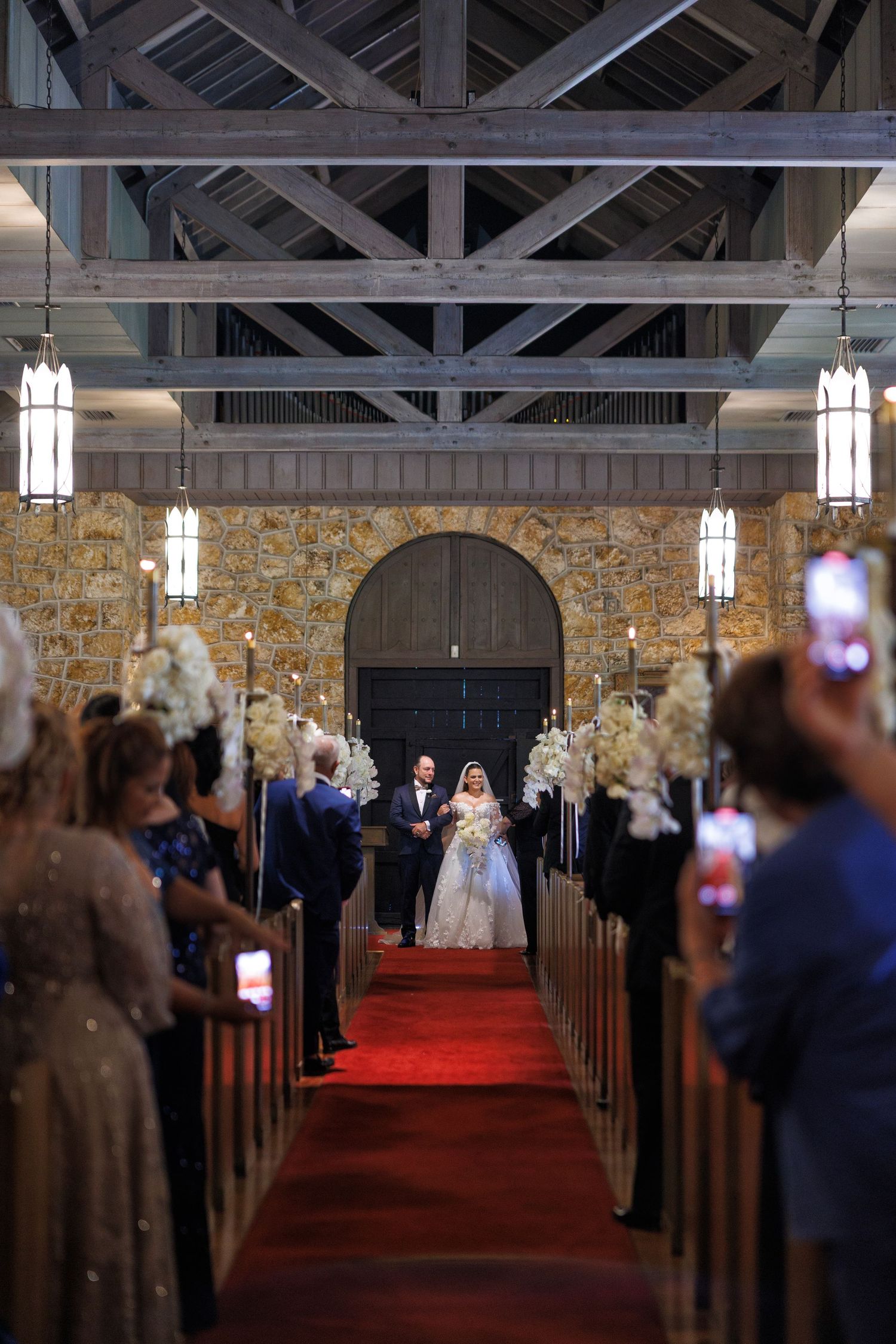 The bride’s grand entrance, golden chandeliers lighting the chapel’s aisle beautifully.
