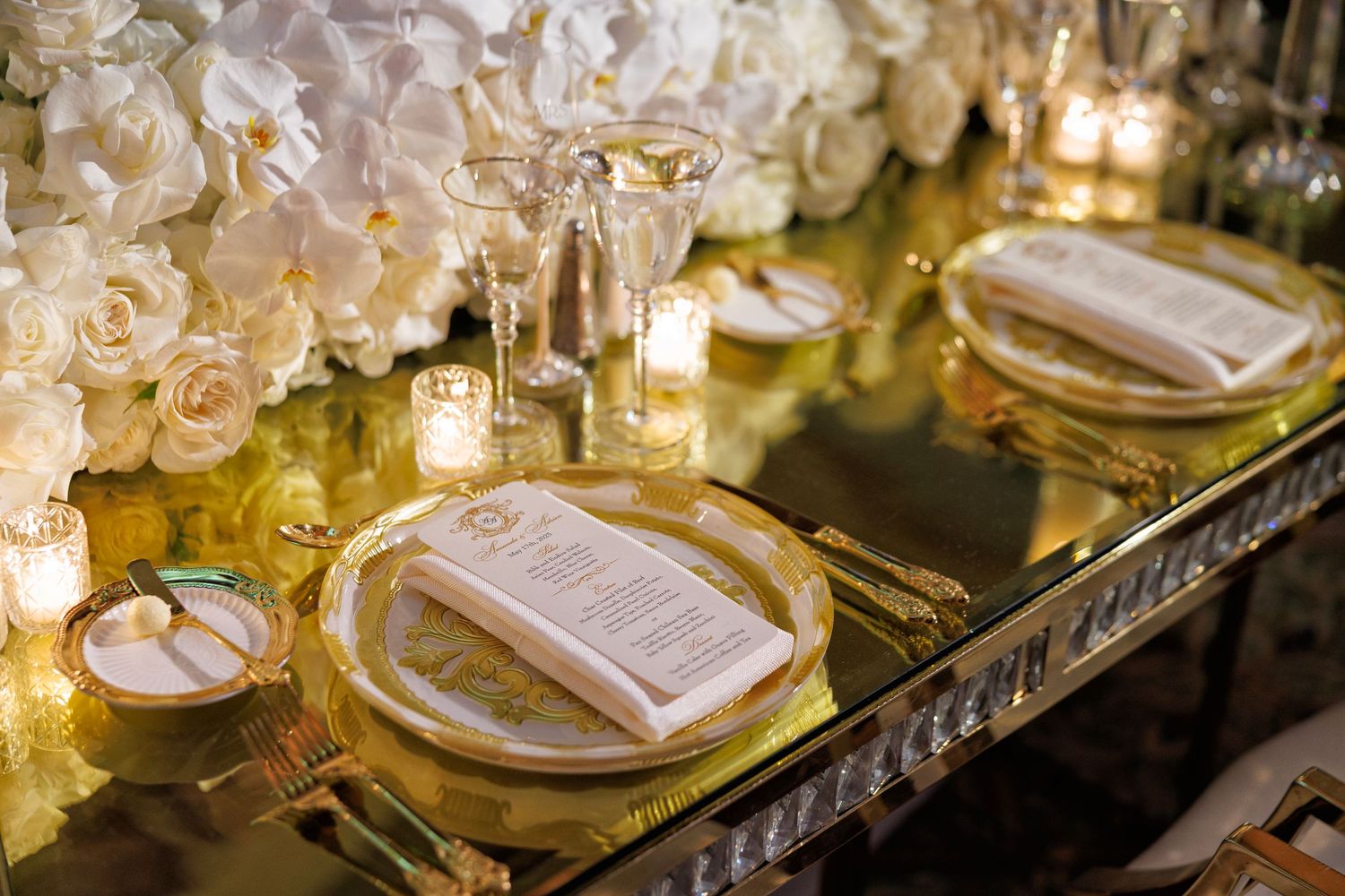 Luxe reception tablescape with gold details, florals, and glowing candlelight.