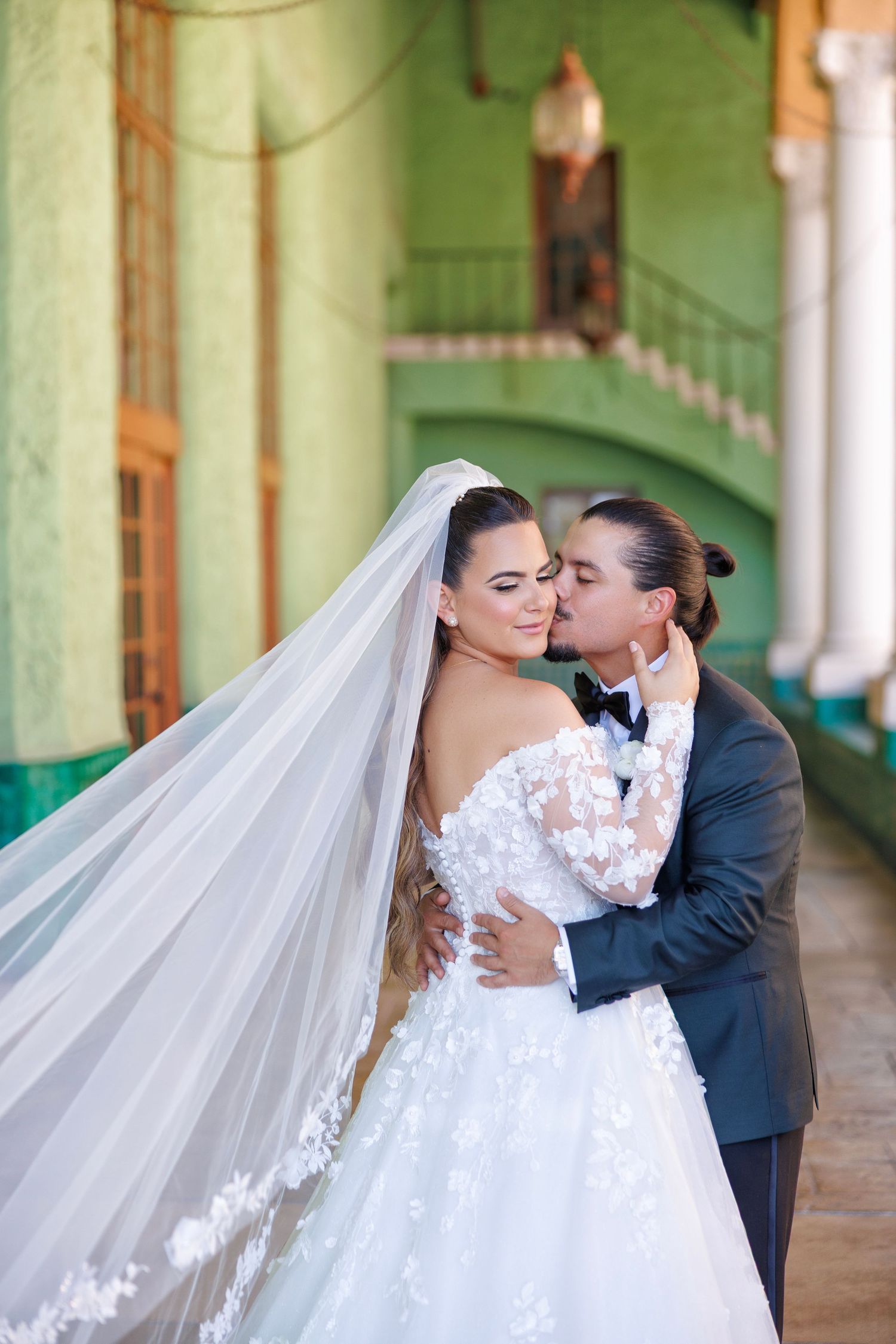 A romantic kiss beneath the bride’s flowing cathedral-length veil.