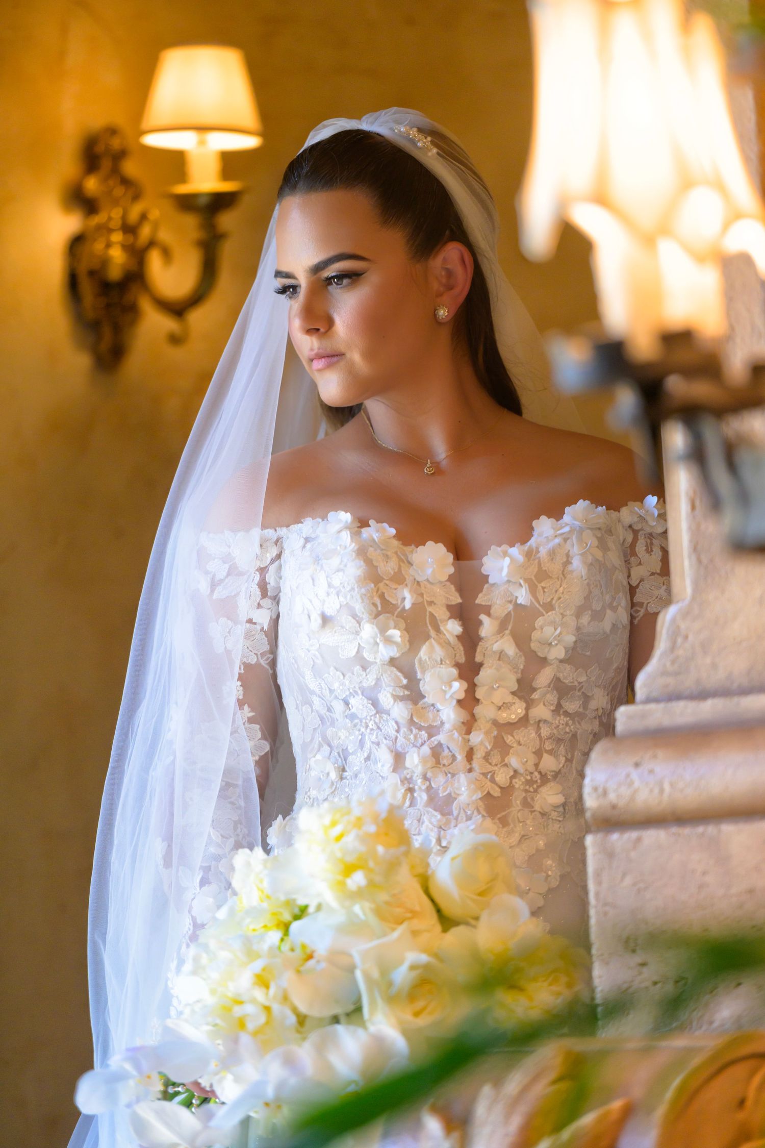 Elegant bride in lace gown with yellow bouquet, standing gracefully before her ceremony.