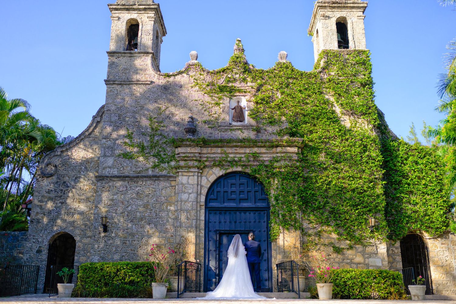 Bride’s gown cascades down the steps of a historic ivy-covered church.