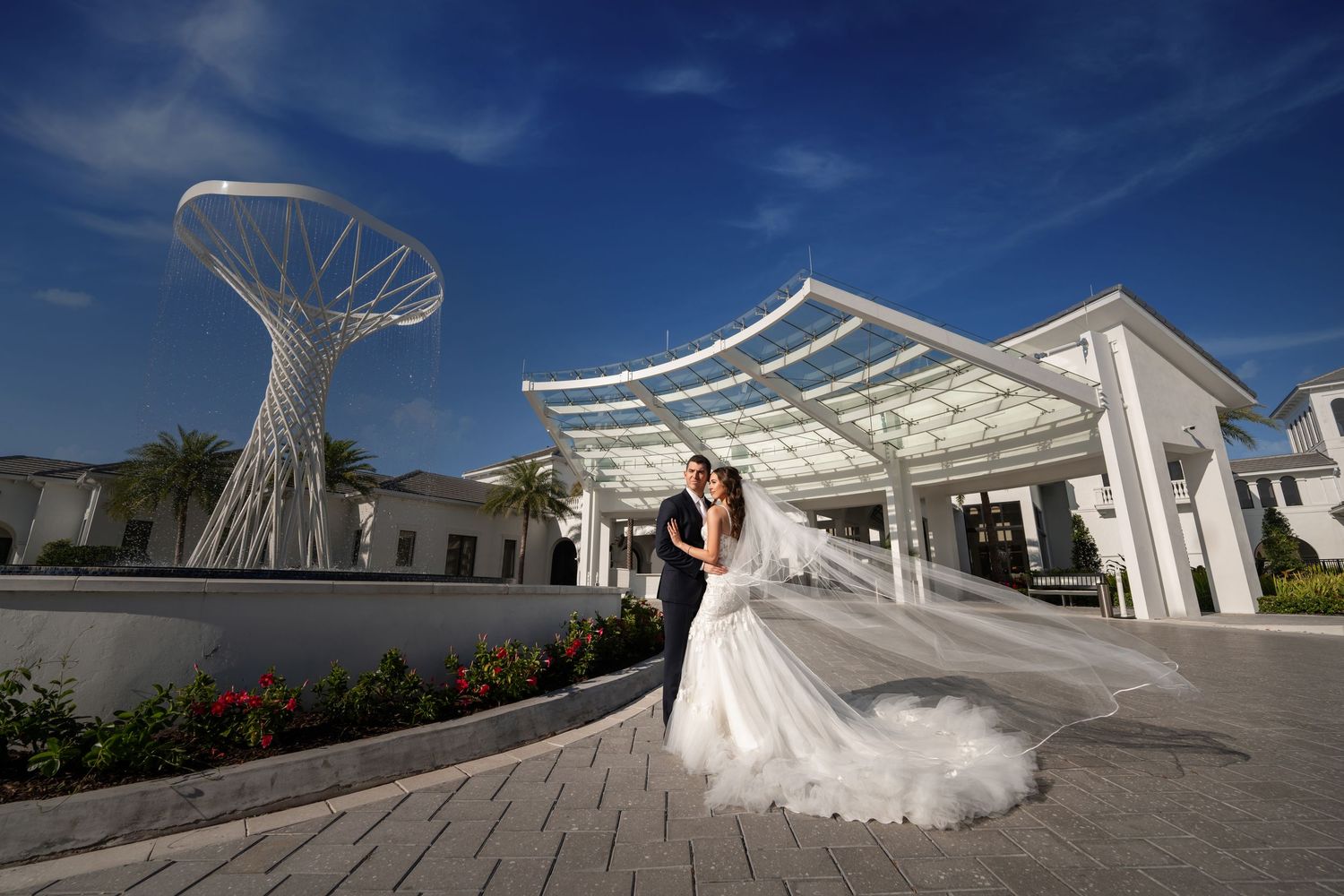 Bride and groom outside a modern white wedding venue—cinematic portrait with architectural backdrop.