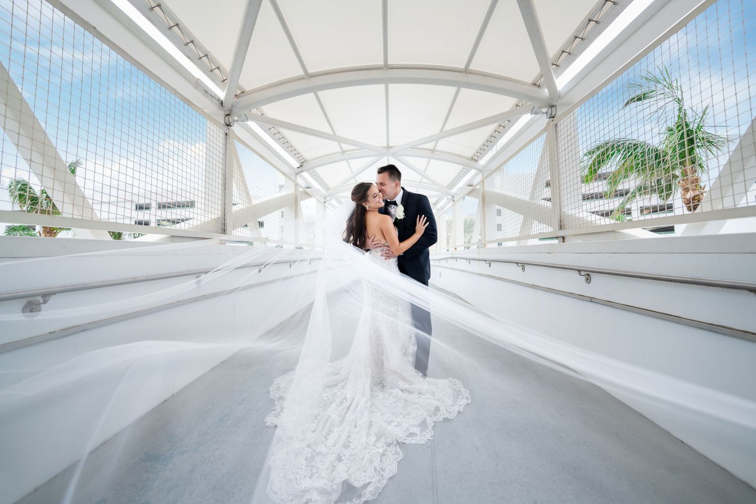 Bride and groom embracing in a modern glass atrium—cinematic wedding portrait with architectural design.