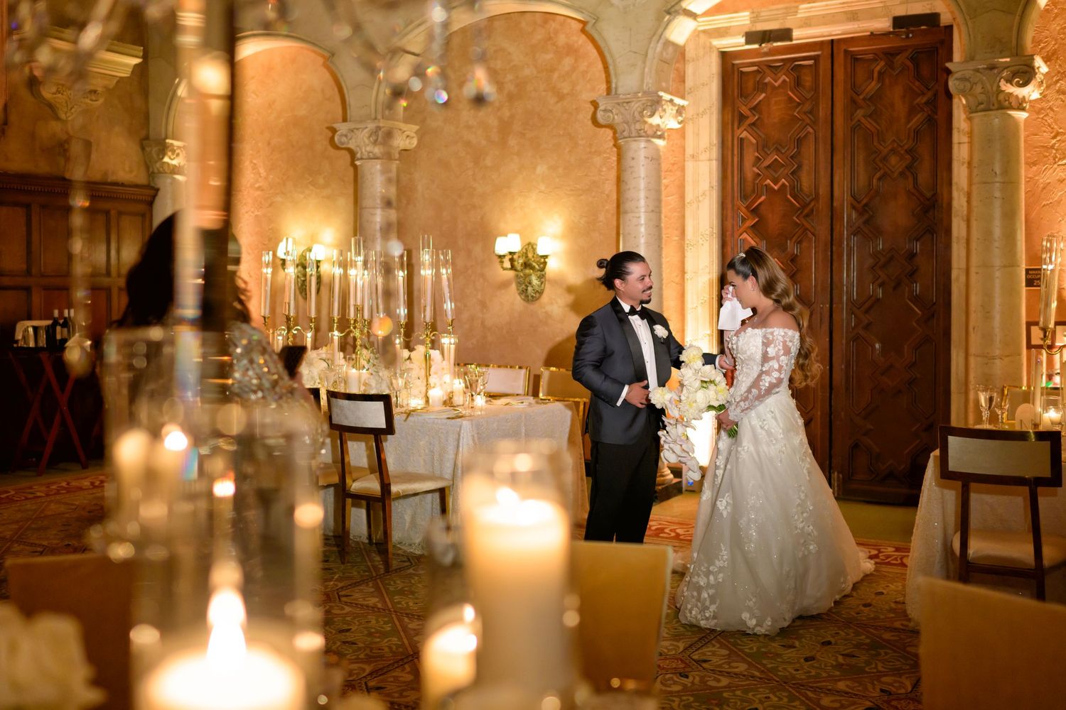 The couple shares a quiet moment, framed by candlelight and timeless elegance.