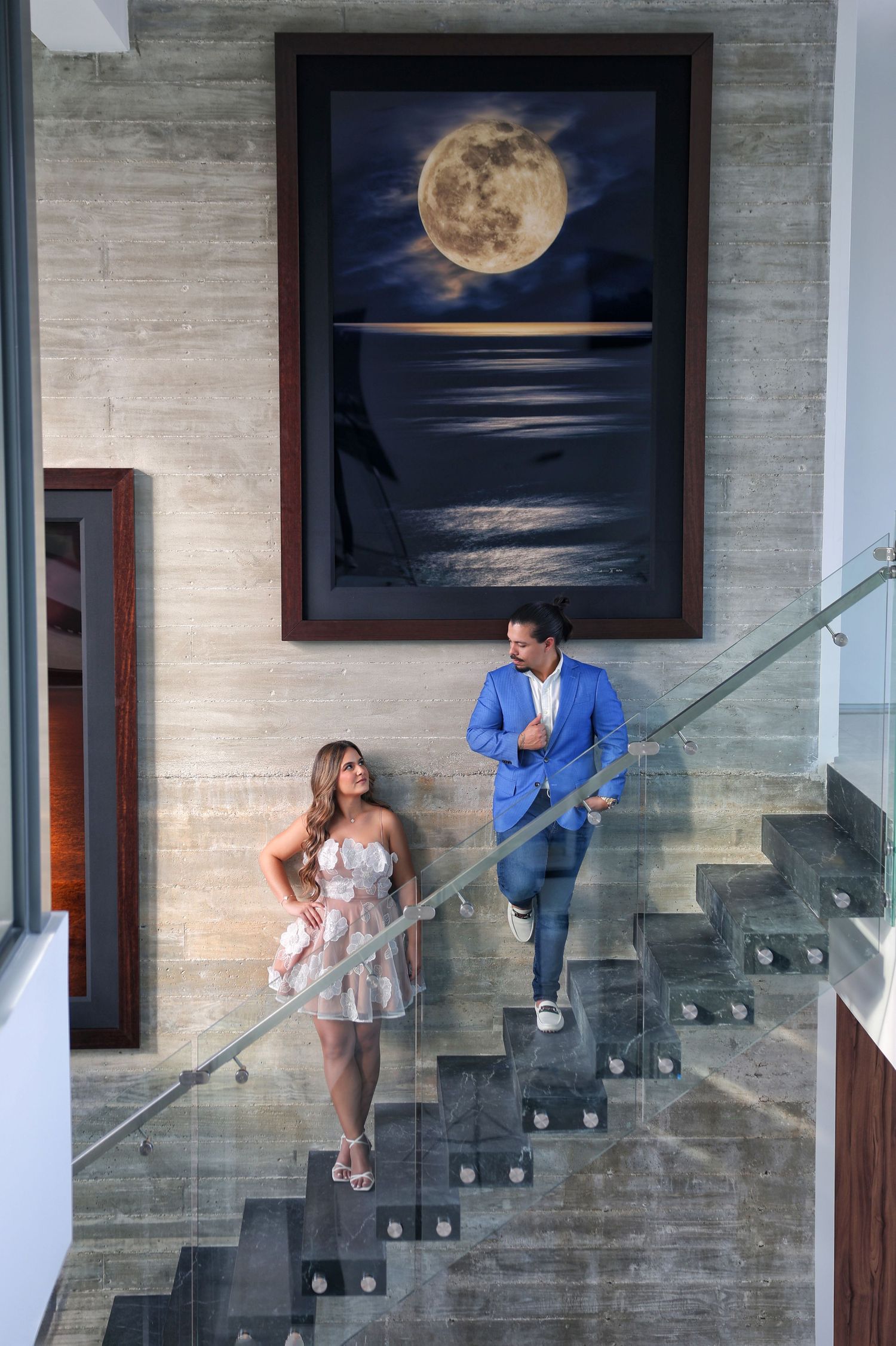 Engagement photo of a couple walking down a dramatic staircase inside a luxury venue—cinematic and refined style.