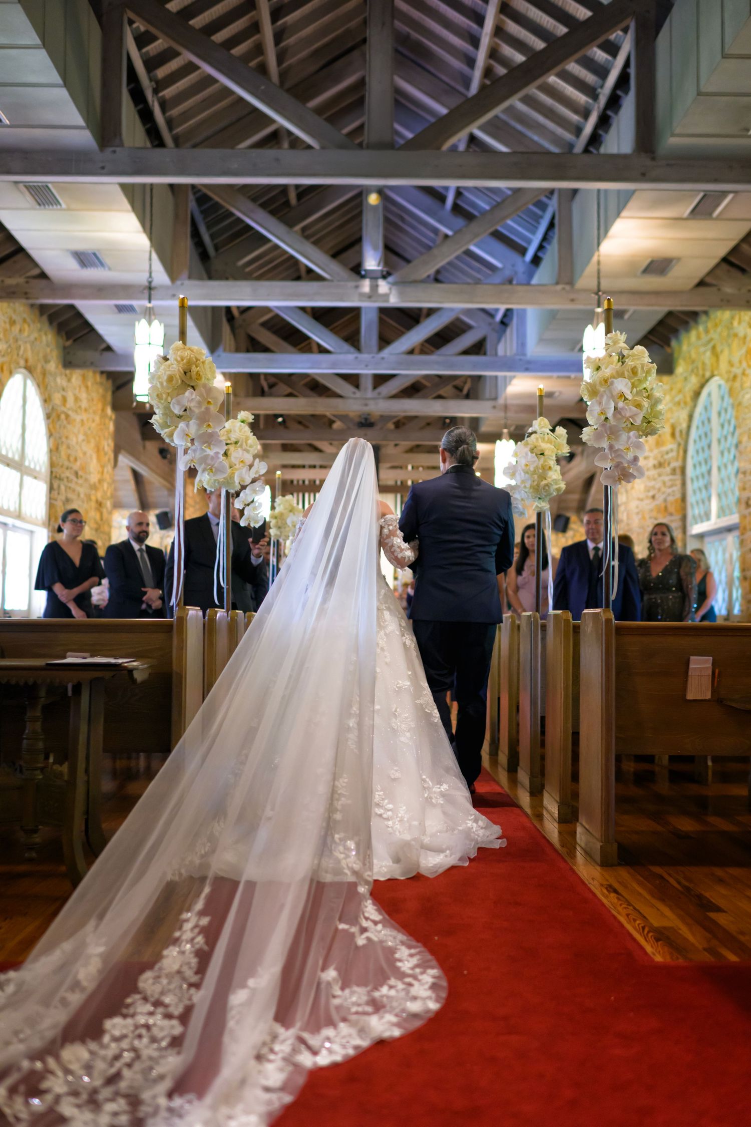 Bride walks down the aisle, her veil trailing behind in a glowing ceremony.