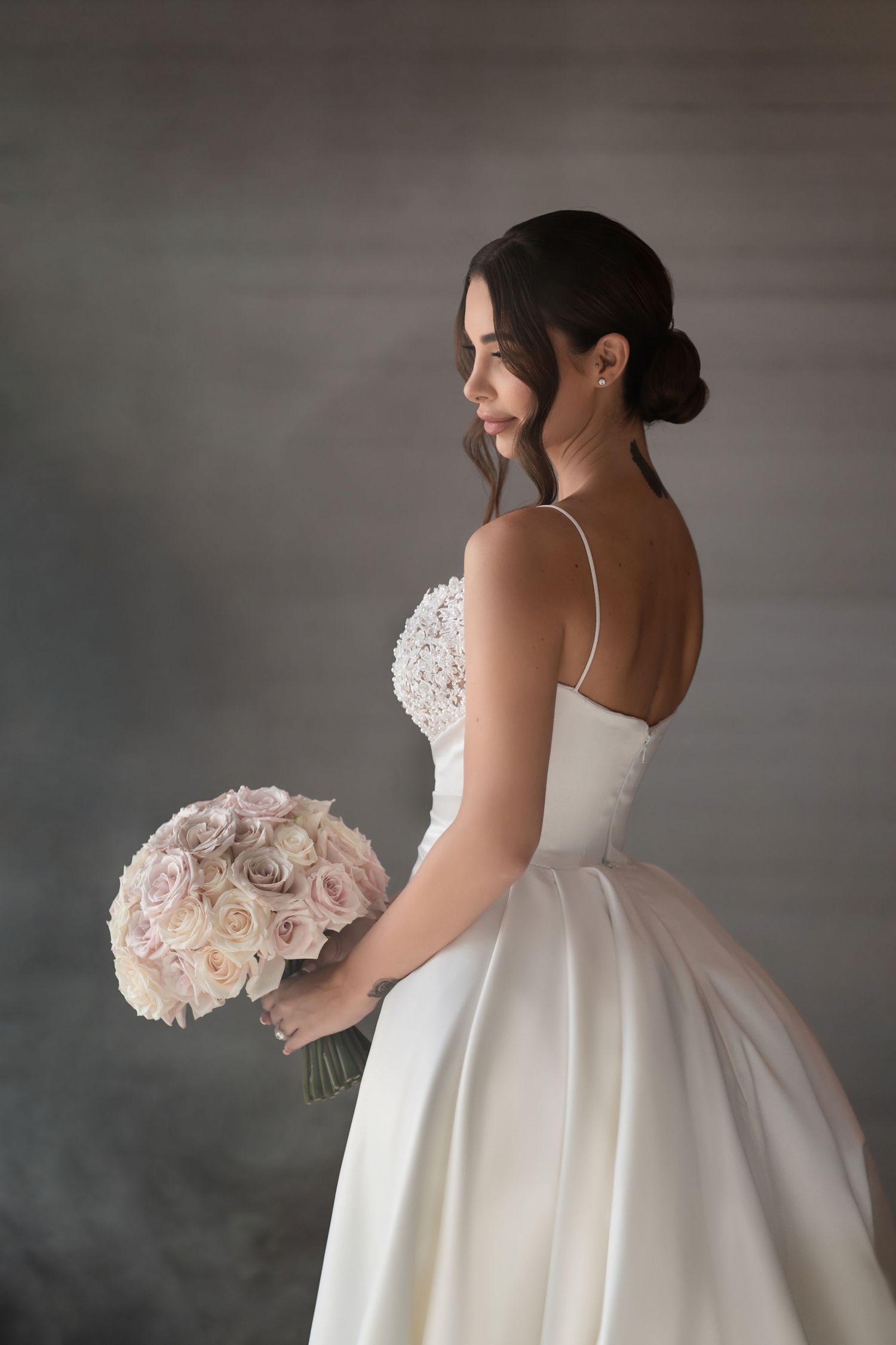 Classic bridal portrait in profile—bride holding a bouquet of pale roses in refined, editorial style.