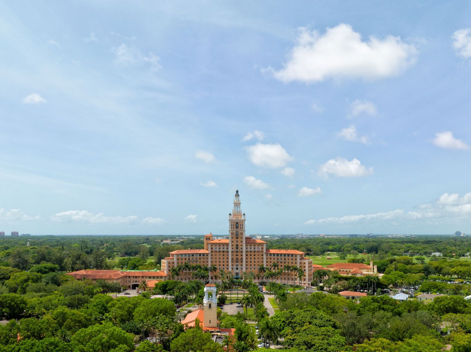 A sweeping drone view of The Biltmore in Coral Gables with its central tower, surrounded by lush greenery.