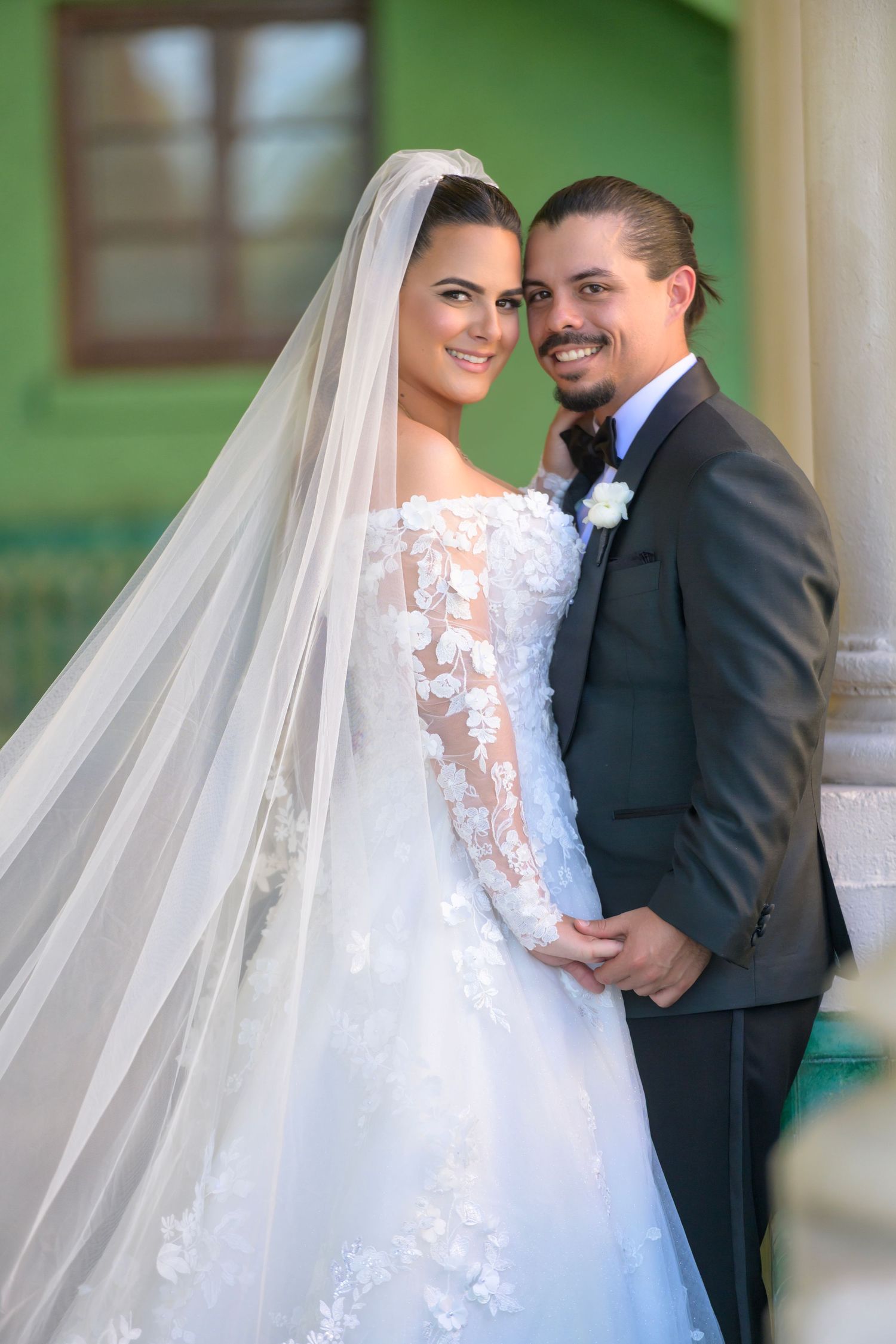 Bride and groom smiling, framed in soft natural light with timeless elegance.