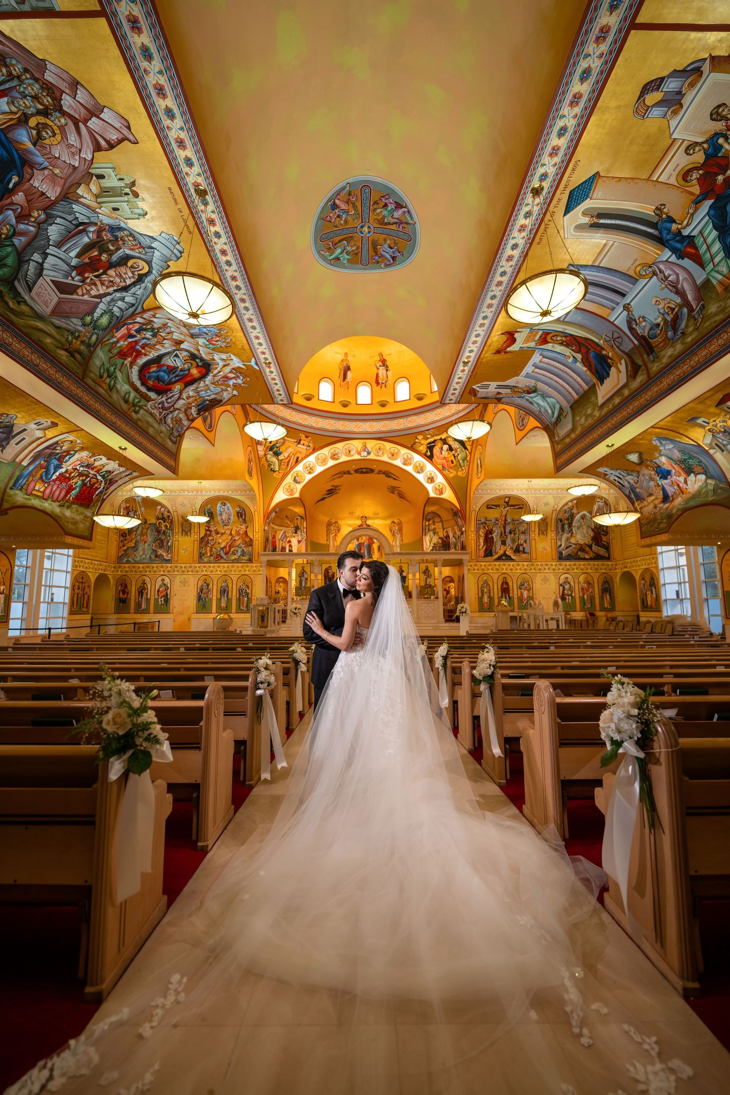 Bride walking down the aisle inside a grand cathedral with golden arches and intricate ceiling frescoes.