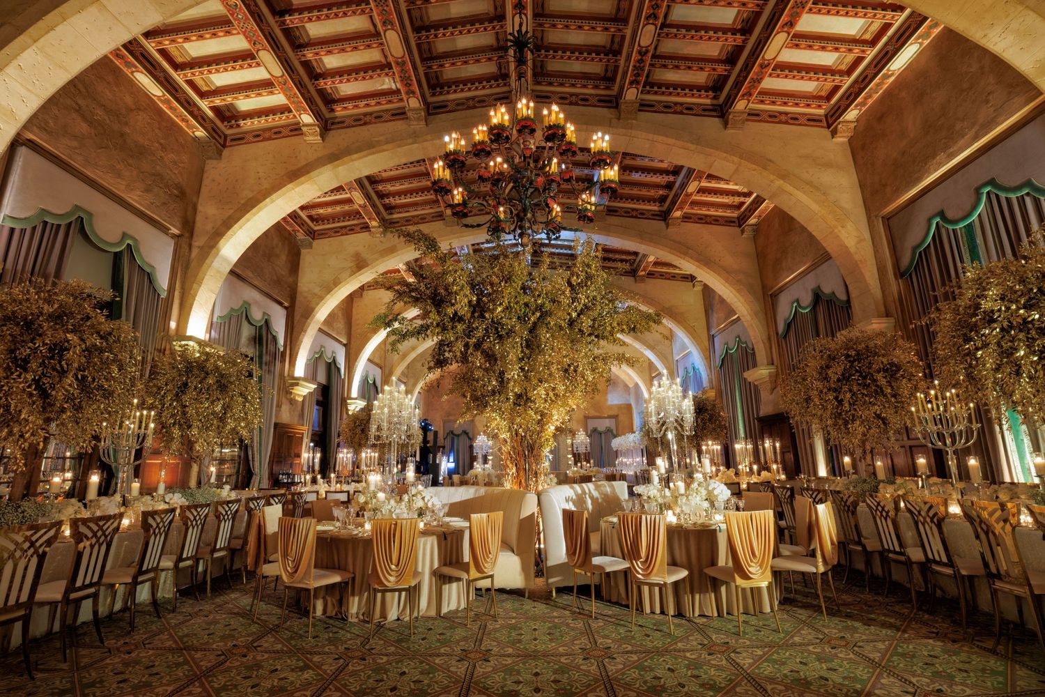 Grand wide shot of the reception hall with chandeliers and warm candlelight.