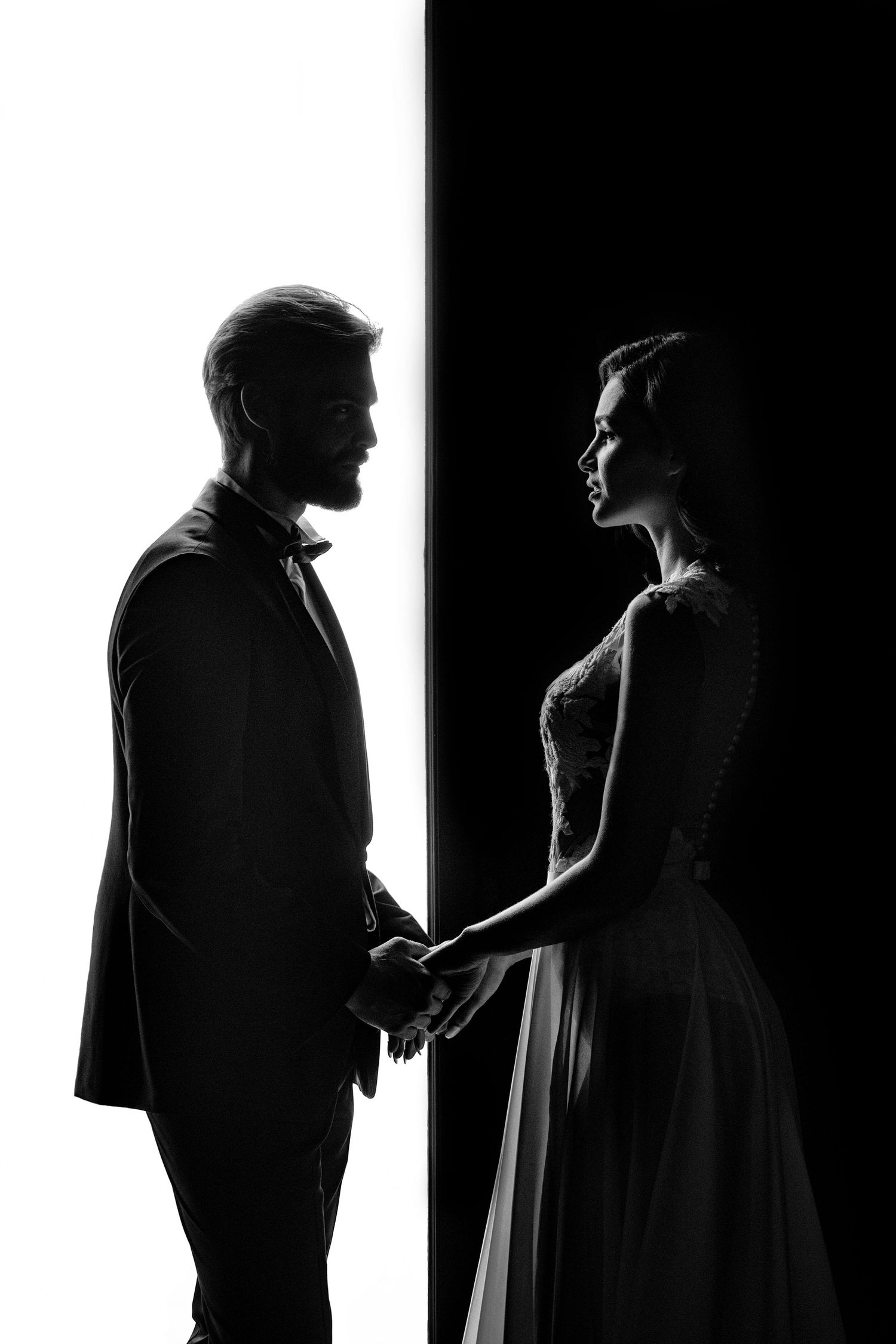 Black and white silhouette portrait of a bride and groom holding hands—artistic wedding photography.