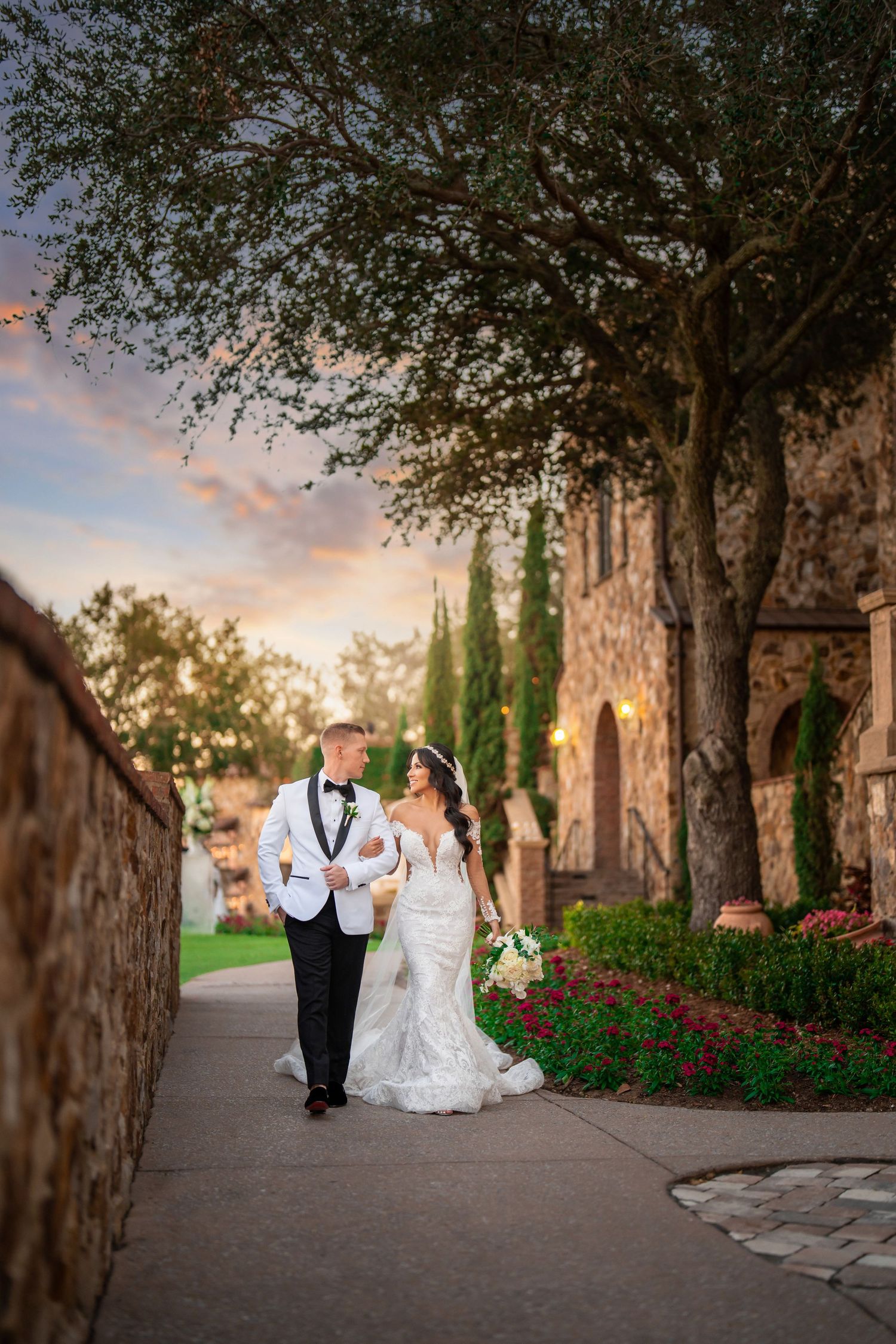 Couple walking hand-in-hand down a charming stone street—romantic wedding portrait at golden hour.