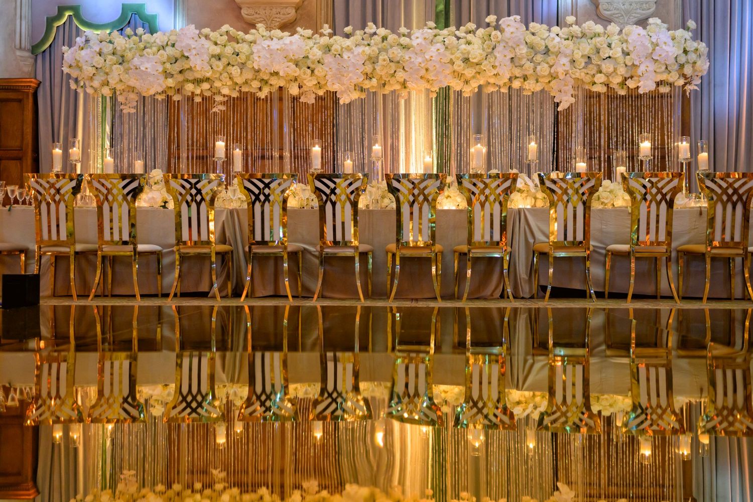 Rows of gold chairs and florals create a breathtaking, regal reception setup.