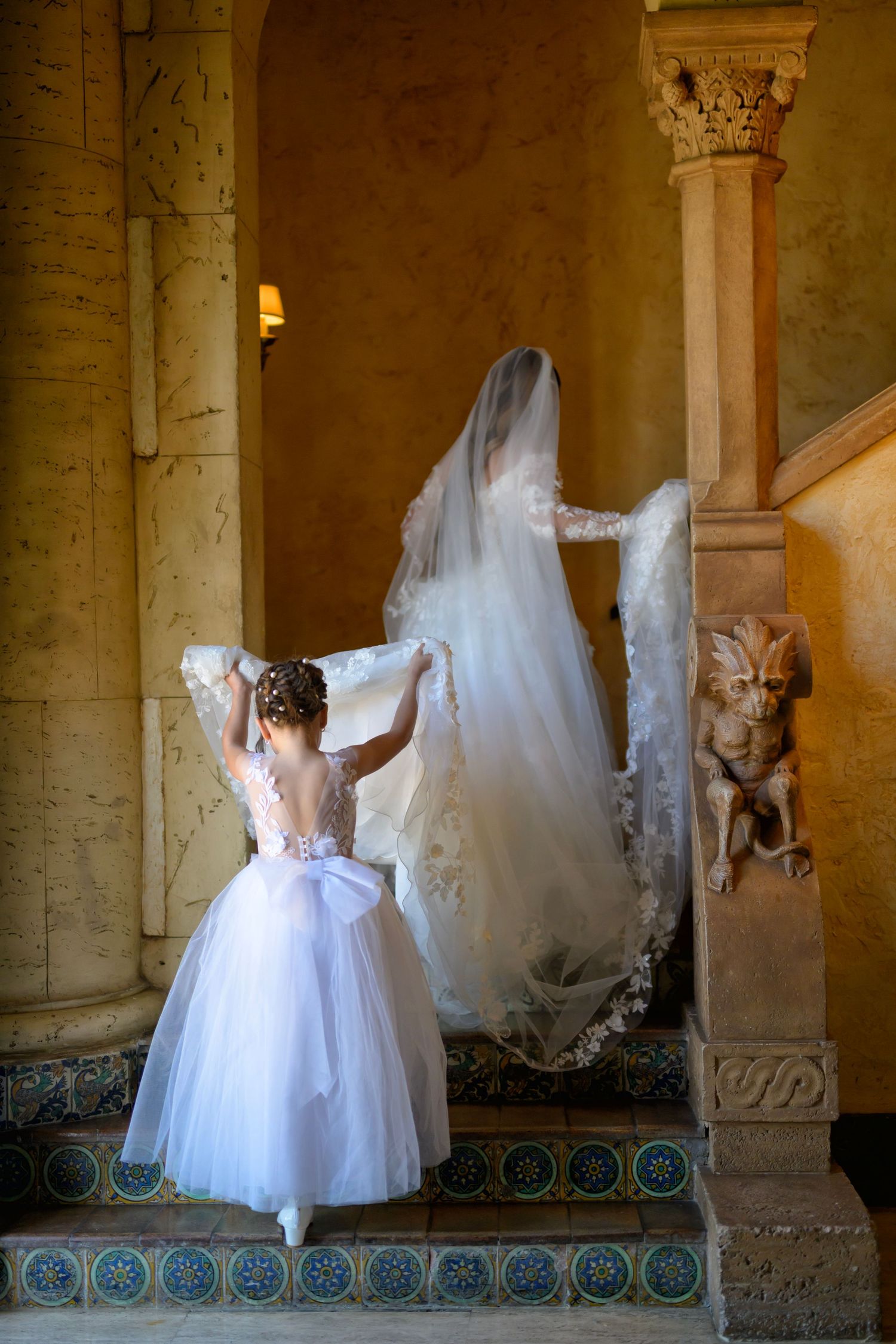 A tender moment as the flower girl carries the bride’s veil before the ceremony.
