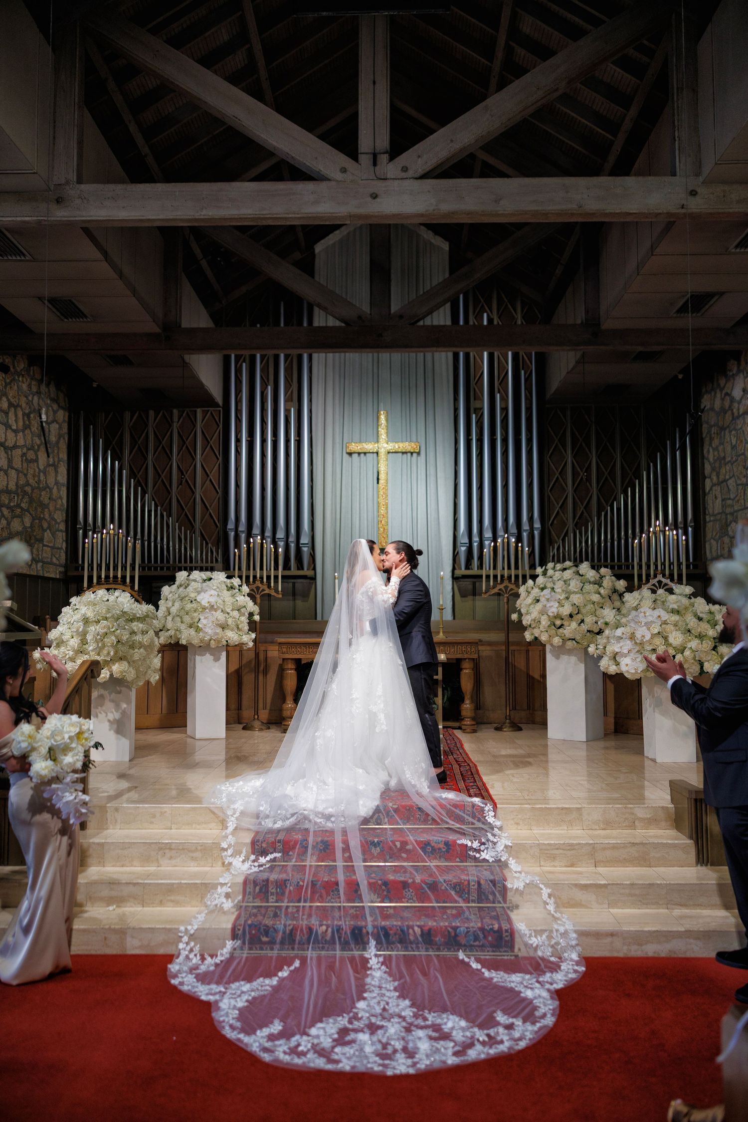 The bride walks down the aisle in her lace gown, framed by a glowing red carpet.
