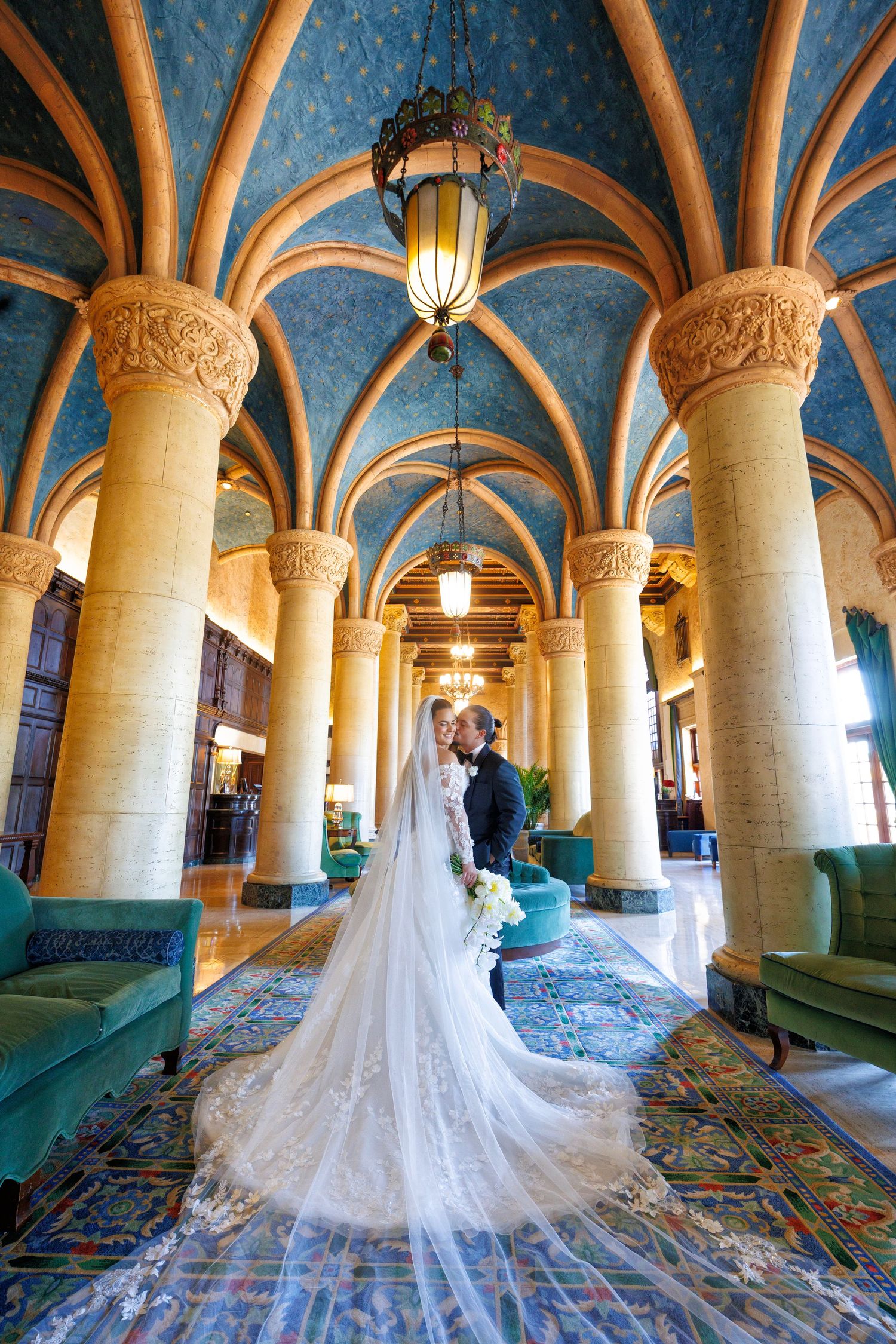 A dramatic aisle moment beneath golden arches, the bride’s veil flowing behind her.