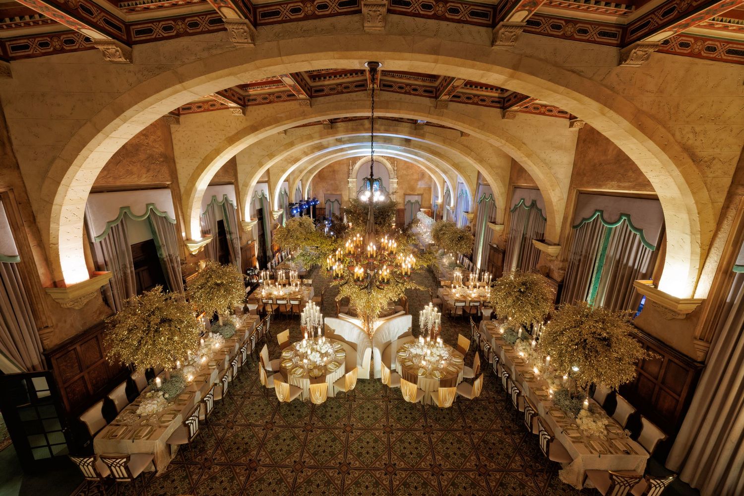 Romantic reception view with arches, florals, and glowing candlelit tables.