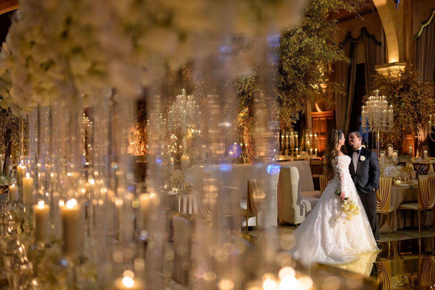 The bride walks through a sea of candles and florals, glowing in golden light.