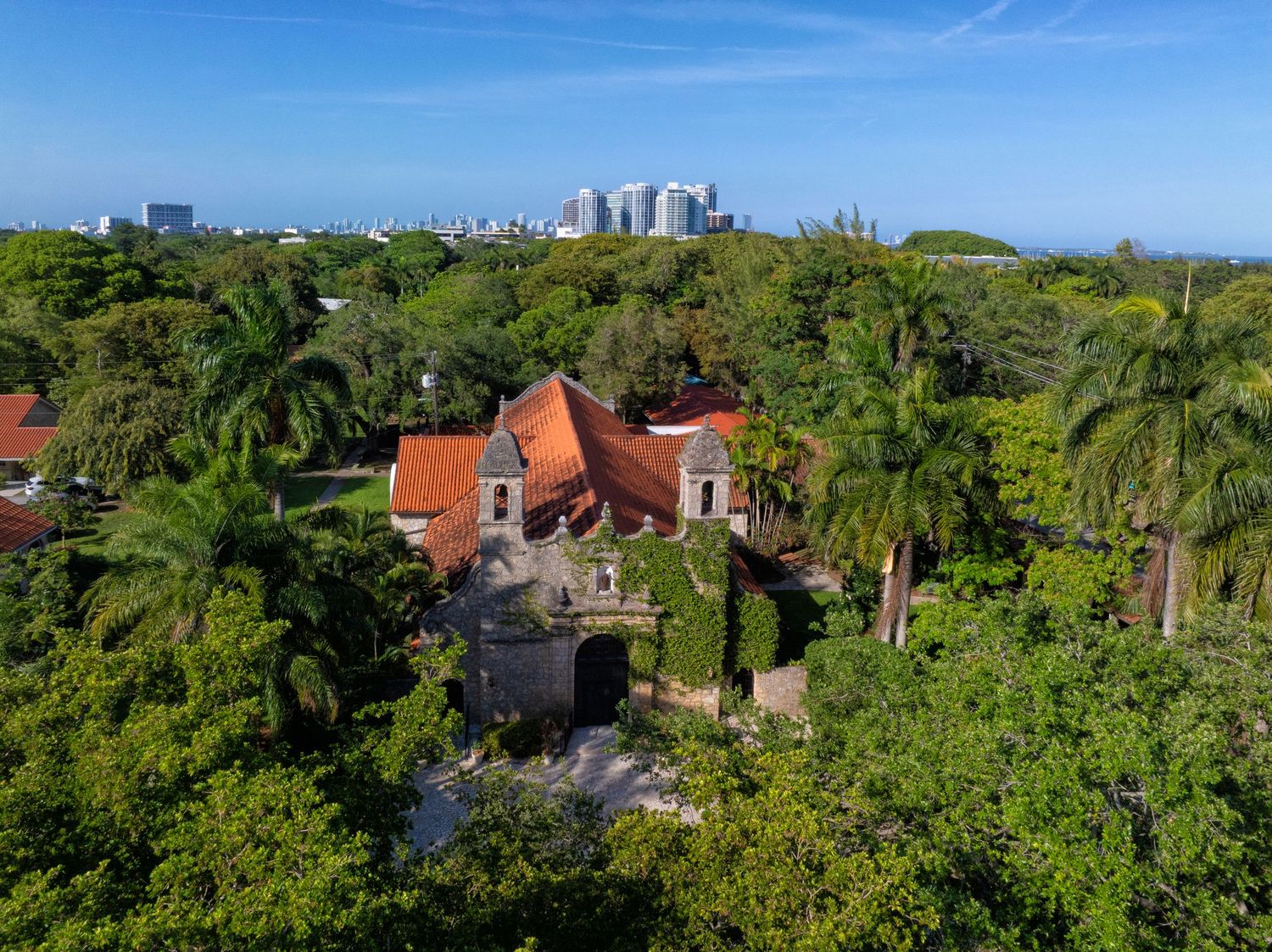 A sweeping drone capture of the venue with the Miami skyline in the distance, blending natural beauty with city sophistication.