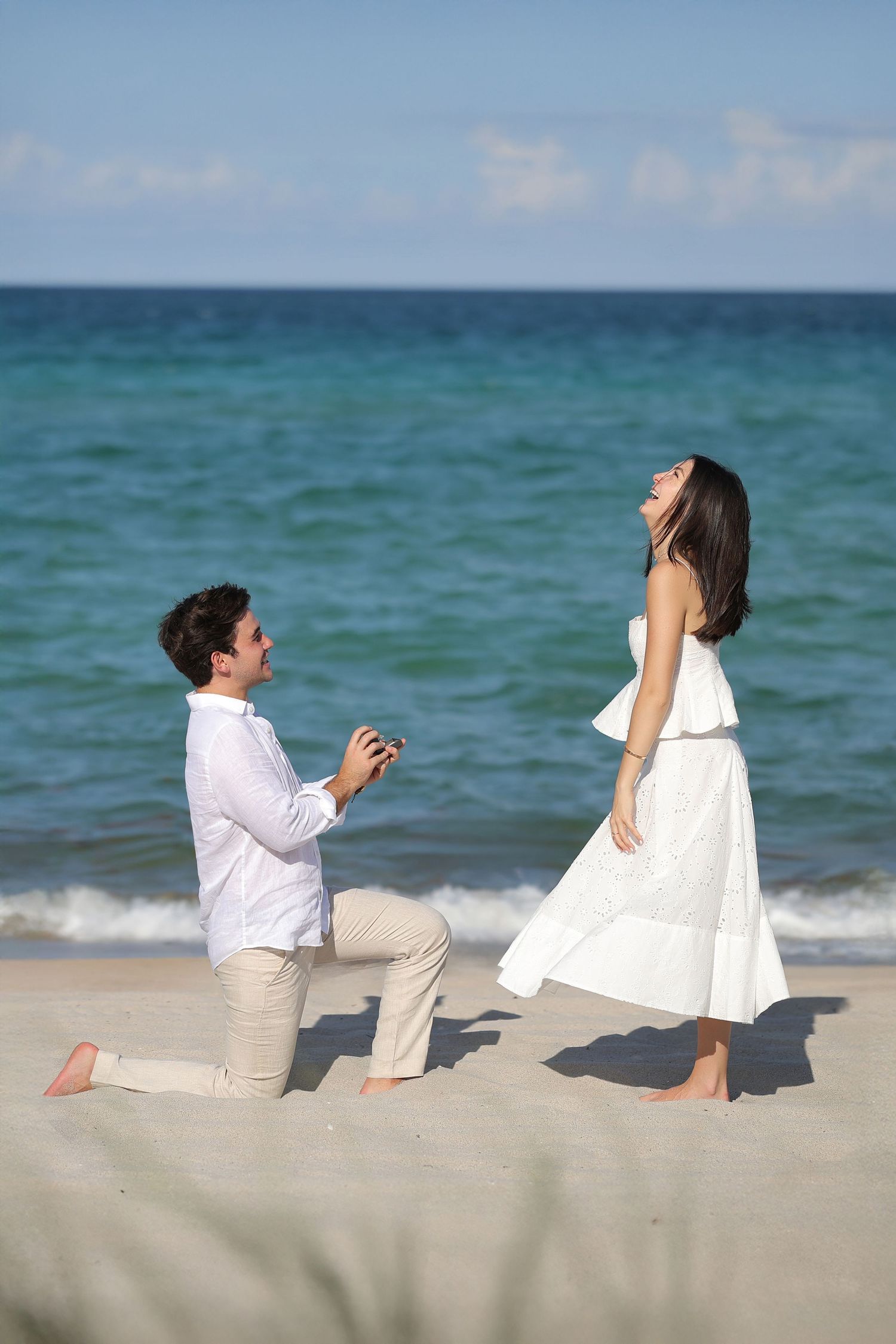 Romantic beach proposal in Miami—groom on one knee as the bride-to-be smiles along the shoreline.
