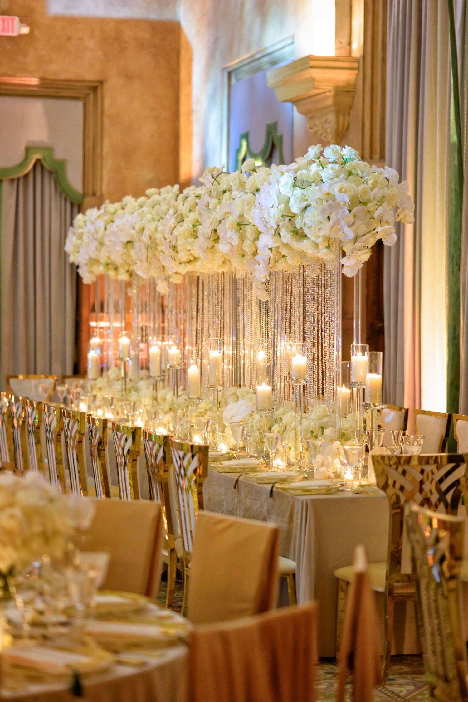 Towering florals and crystal glassware shine under warm light.