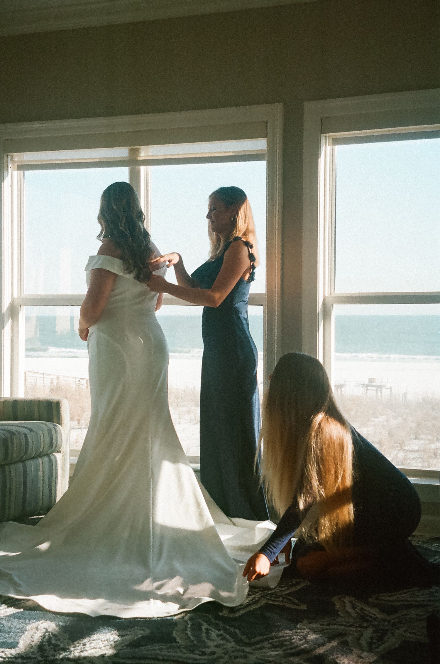 Bride getting ready with bridesmaids inside a beachfront Airbnb before her wedding