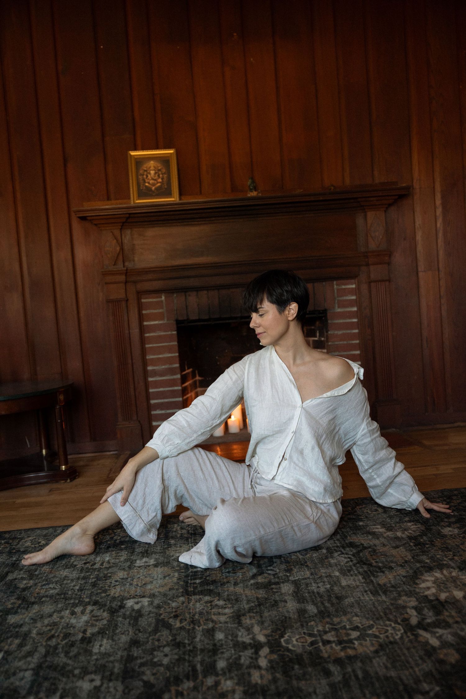 Portrait of a woman seated in front of a fireplace with natural light