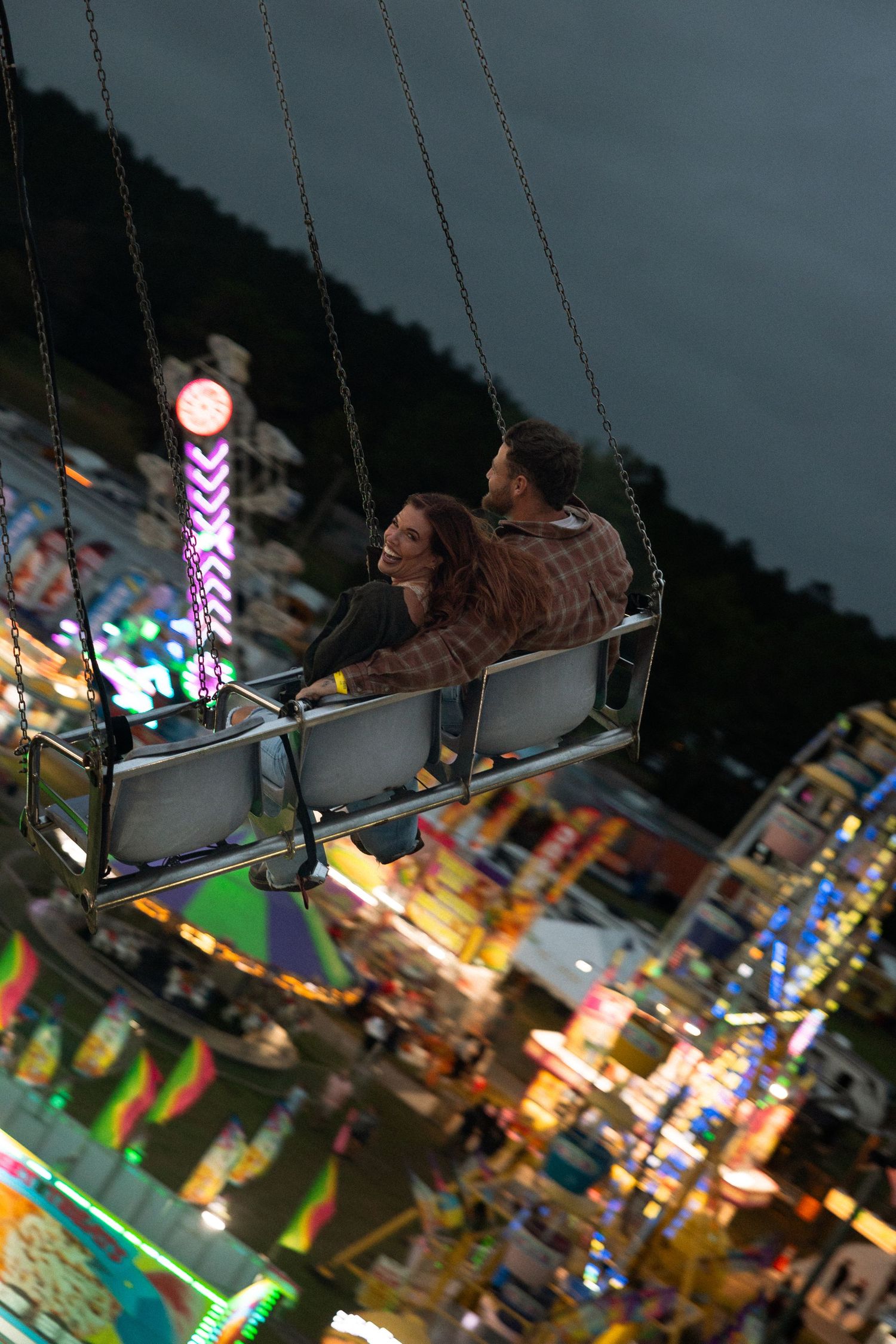 Couple riding carnival rides during a playful fair photoshoot