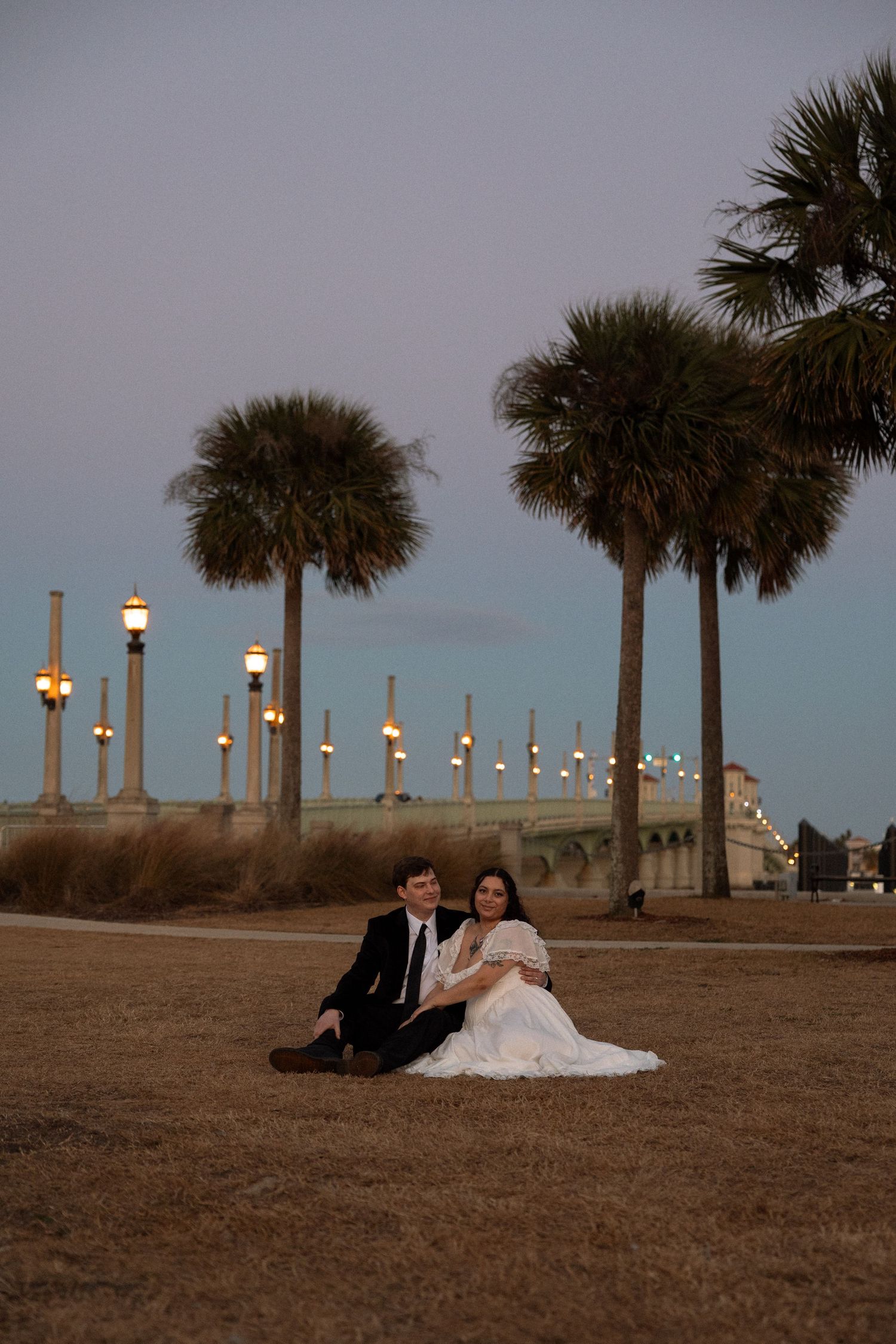 Couple sitting in the grass at sunset along the St. Augustine waterfront