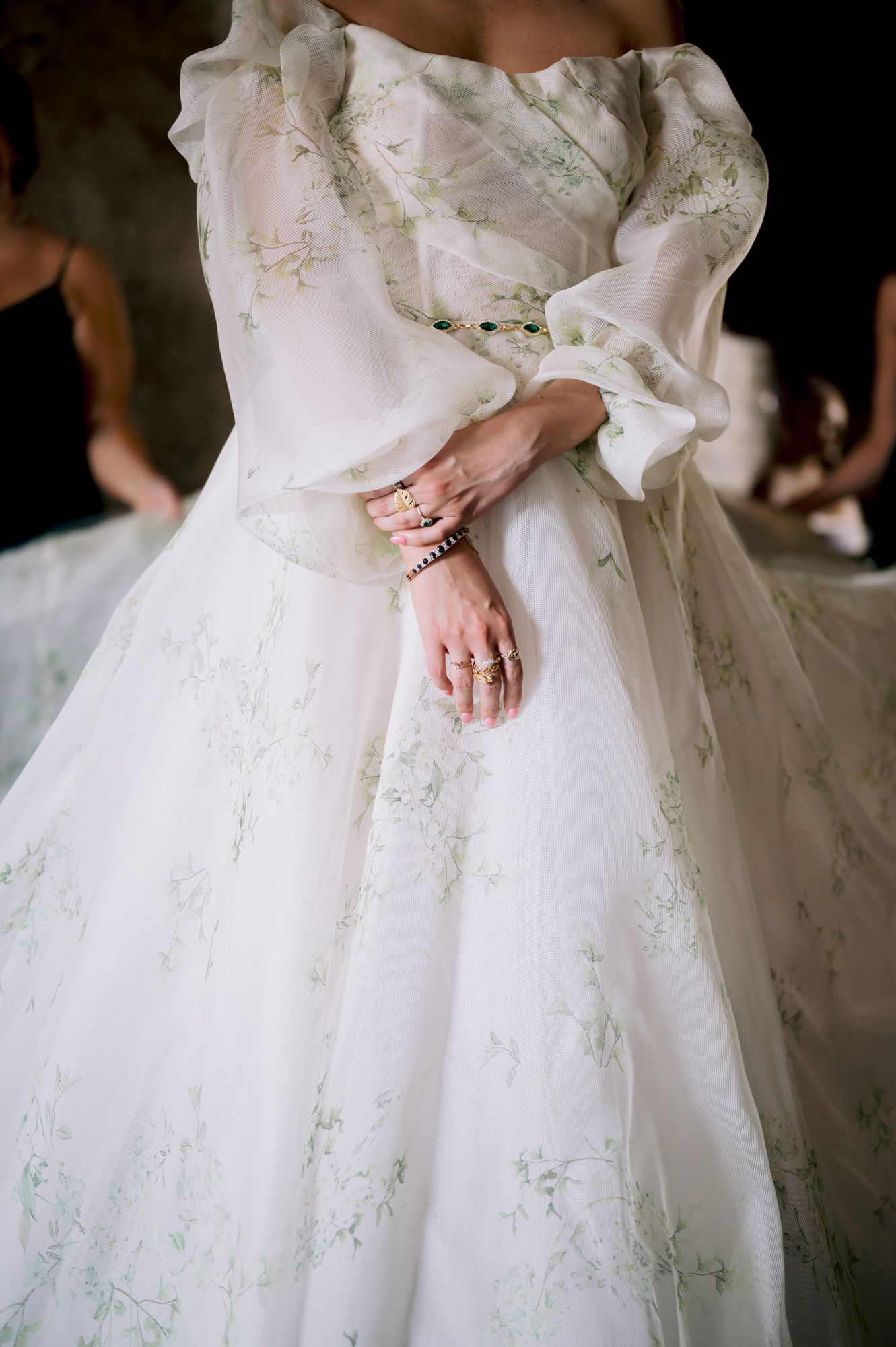 Close-up detail of a white wedding gown with delicate floral embroidery and jewelry on the wearer's wrist.