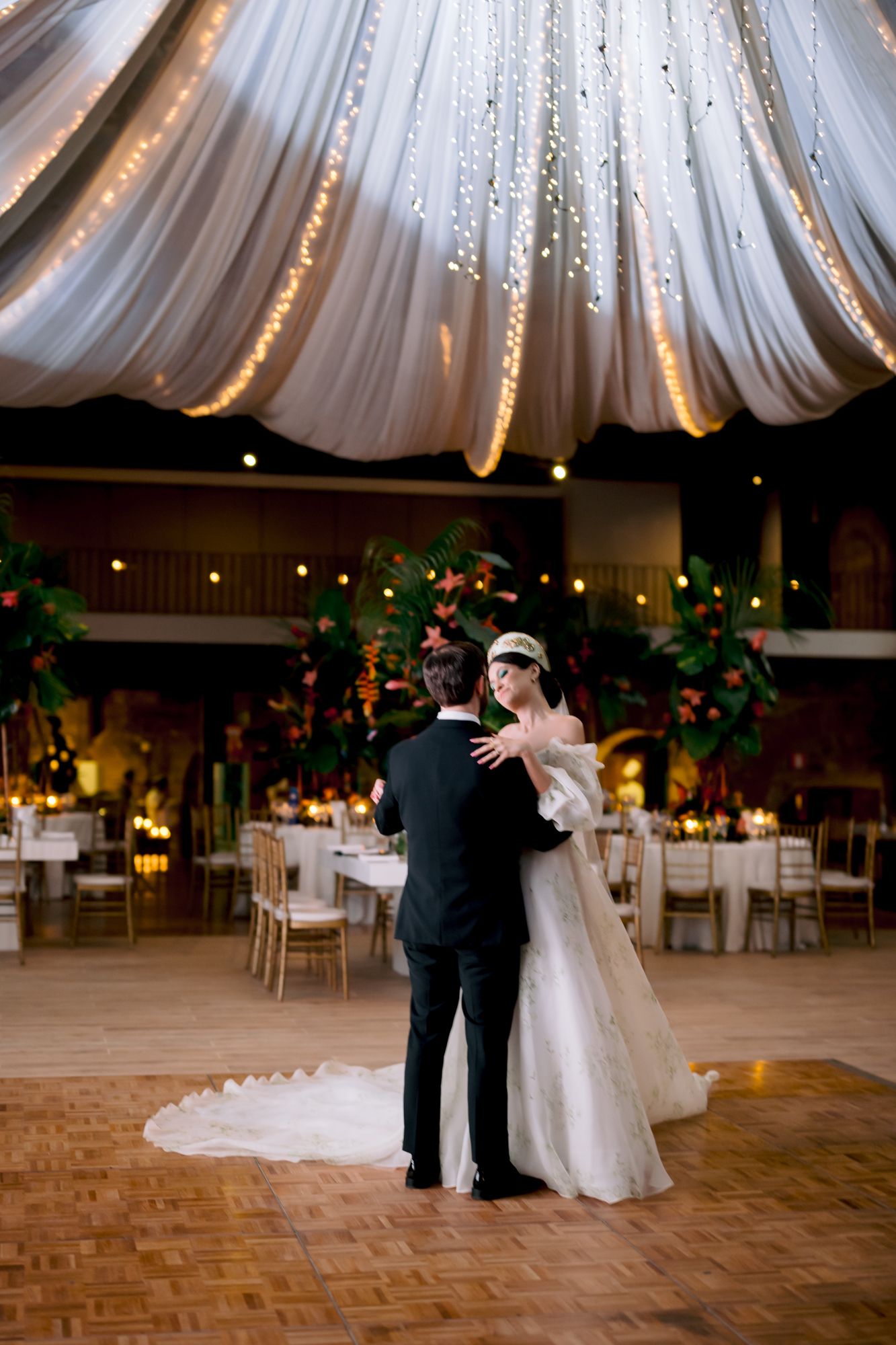 First dance under twinkling draped fabric ceiling at elegant reception venue.