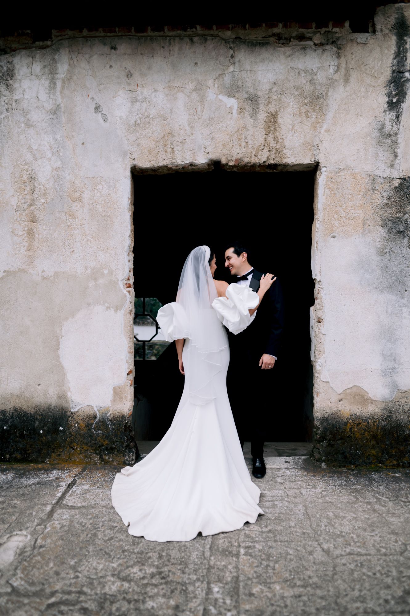A romantic wedding pose framed within a white stone doorway at a historic venue.