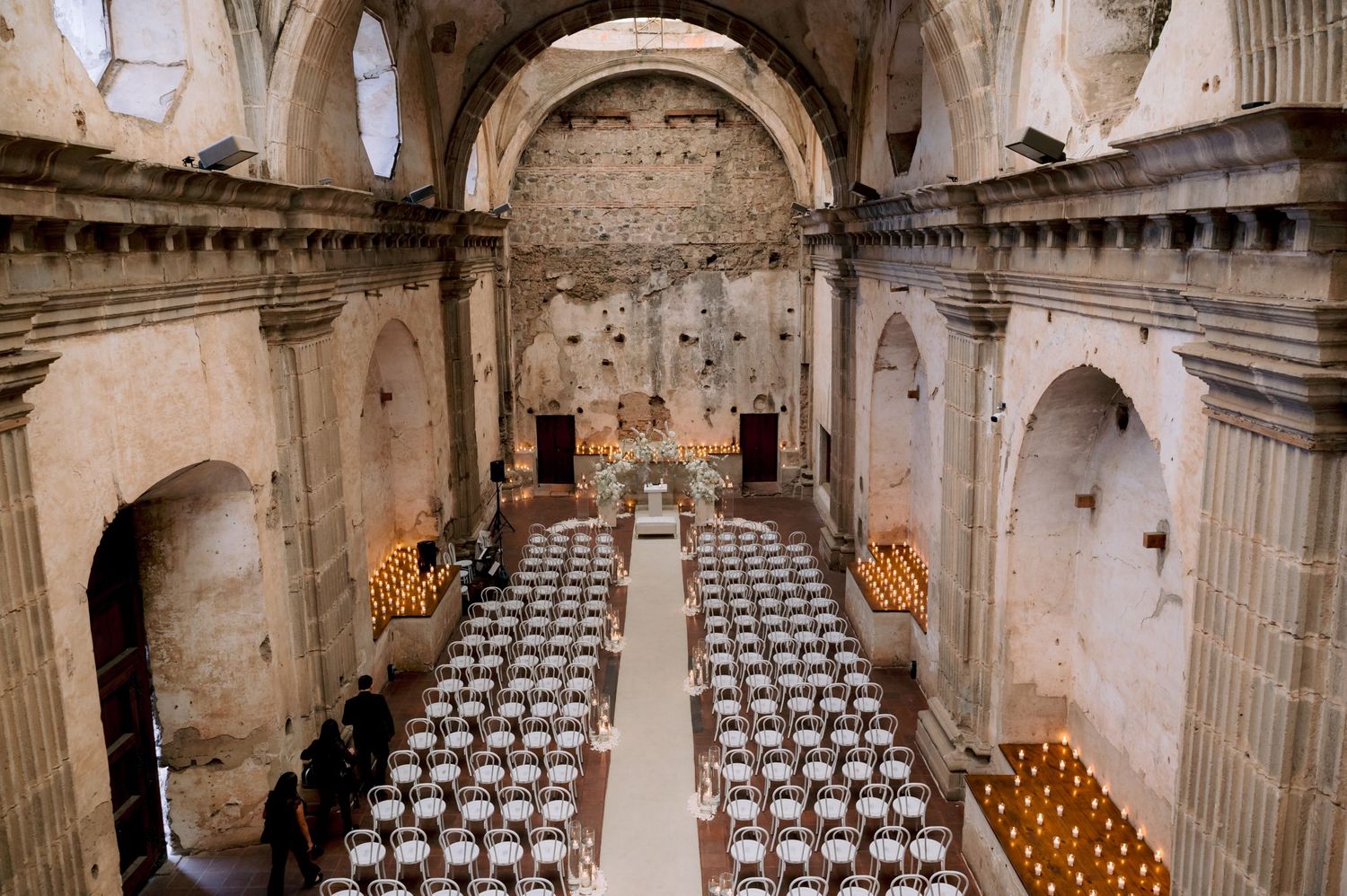 Historic church interior set up for wedding ceremony with white chairs and vaulted stone architecture.