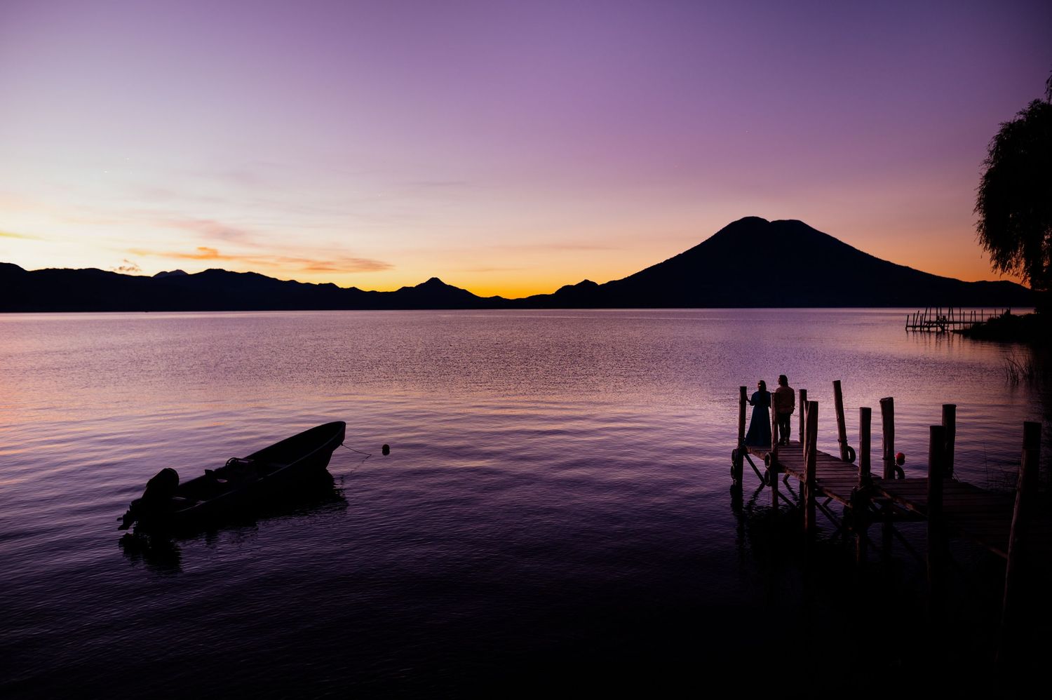 A series of serene lake sunset scenes with silhouetted docks and mountains reflecting on calm purple waters.