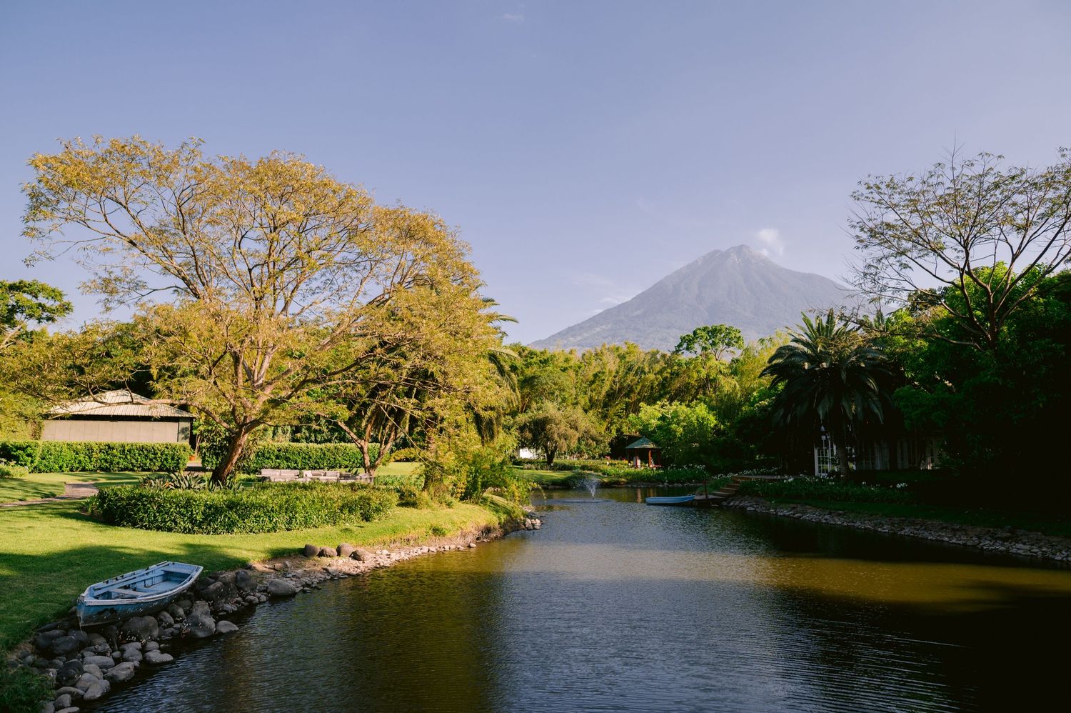 Scenic view of a mountain peak reflected in a serene pond surrounded by autumn-colored trees and greenery.