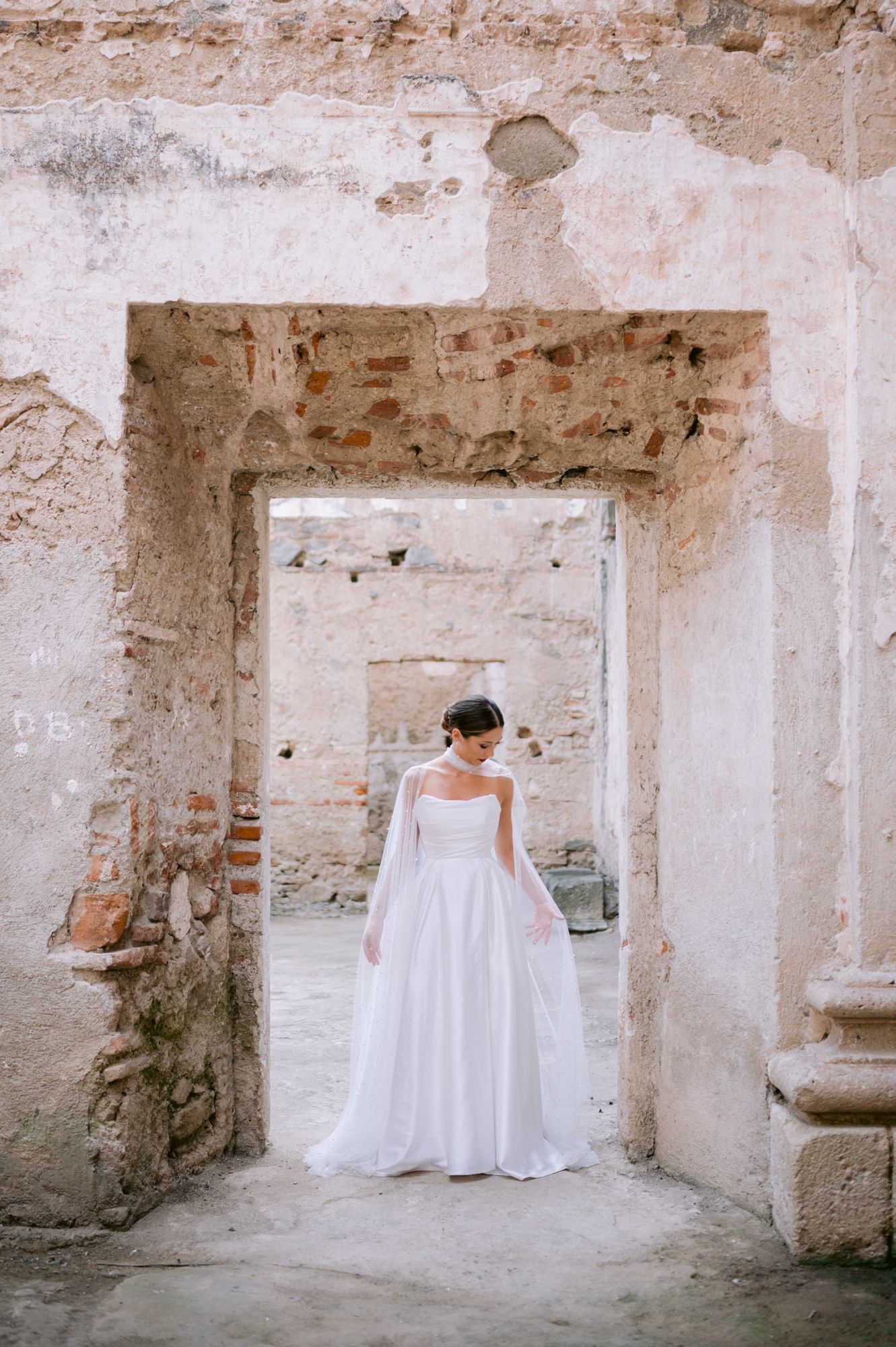 Wedding dress photoshoot in aged stone doorway showing classic white gown silhouette.