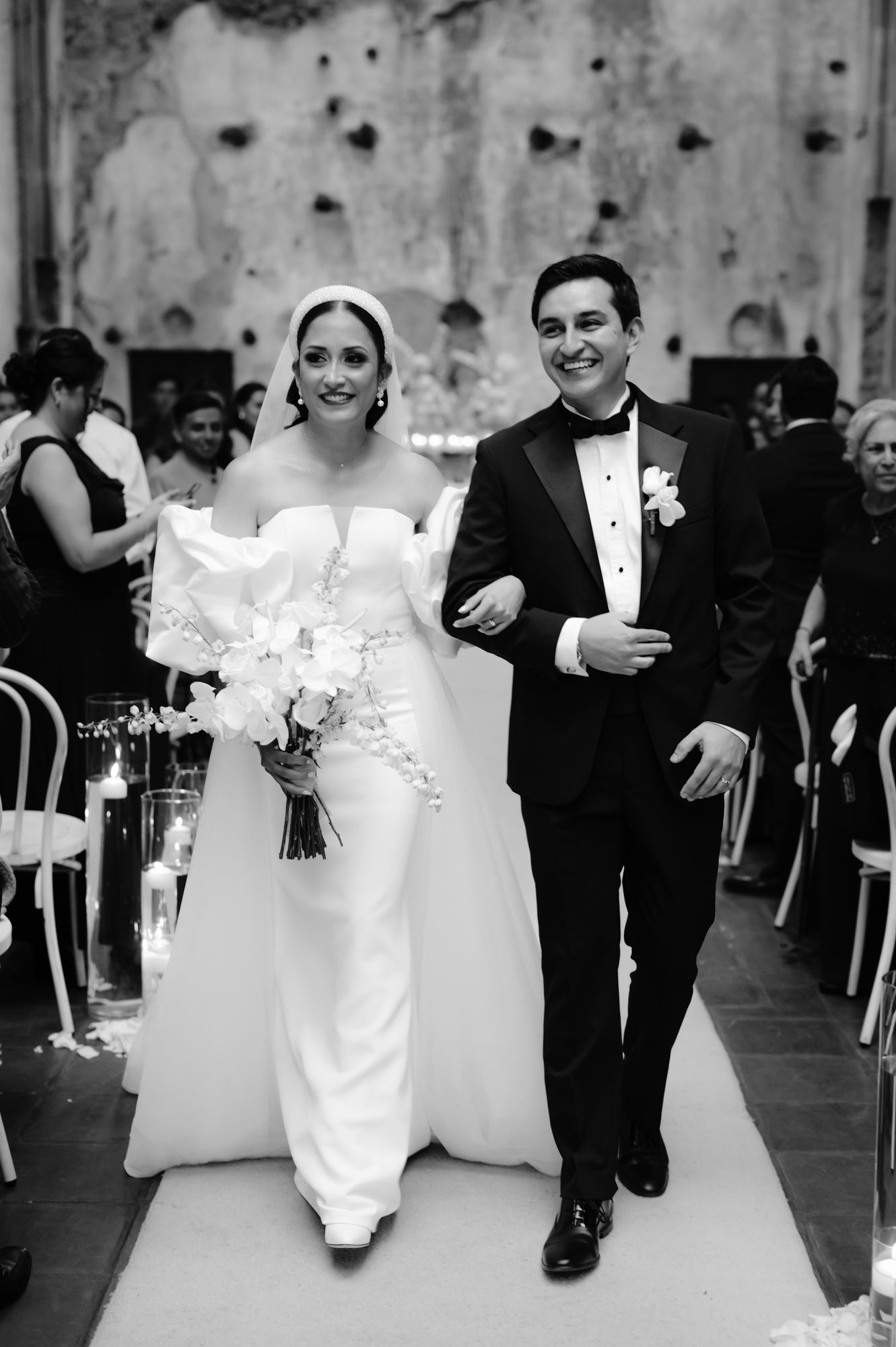 A couple walks down the aisle together in formal wedding attire during their ceremony.