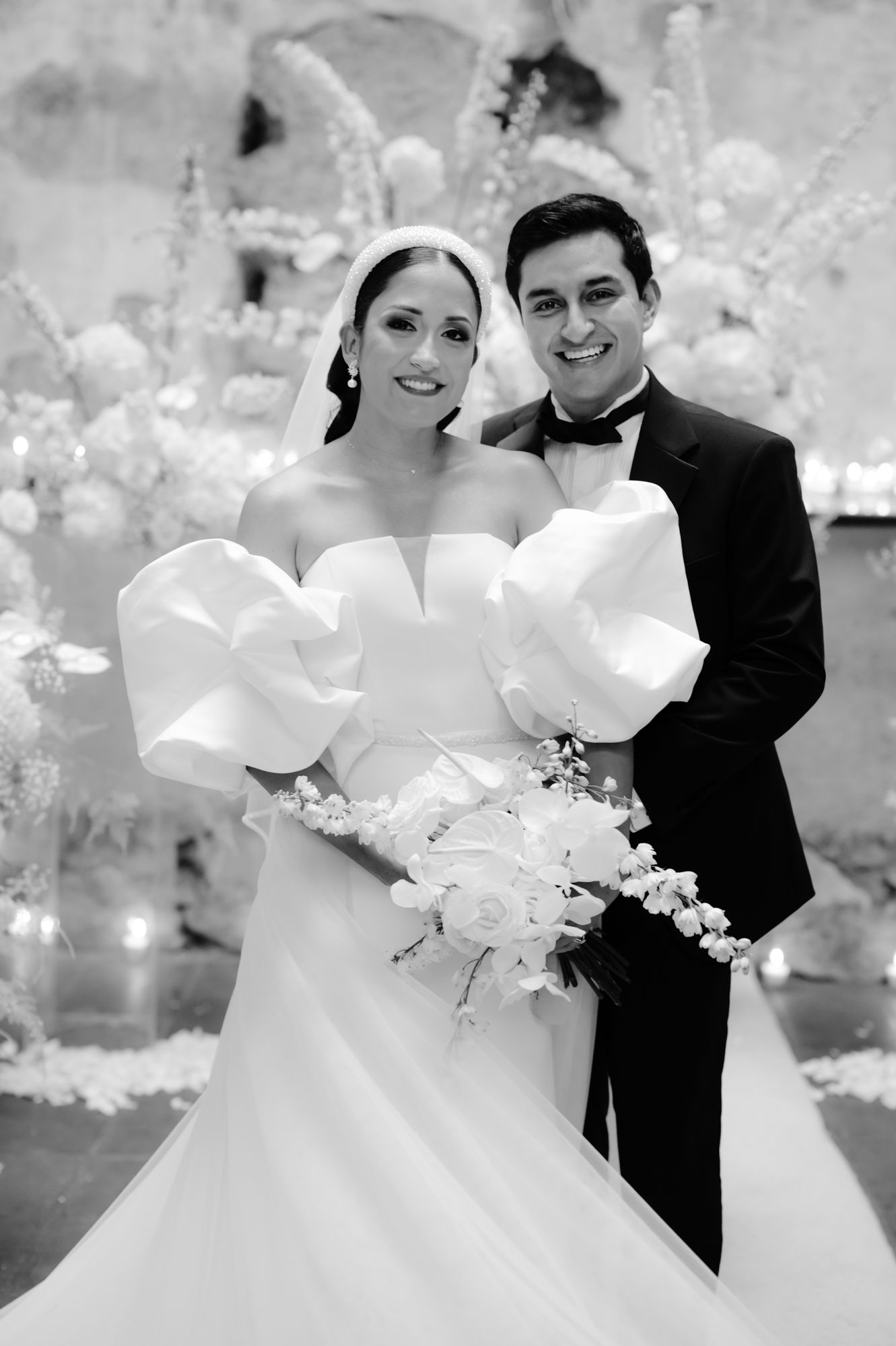 Black and white portrait of newlyweds with stunning white bouquet against ethereal background.